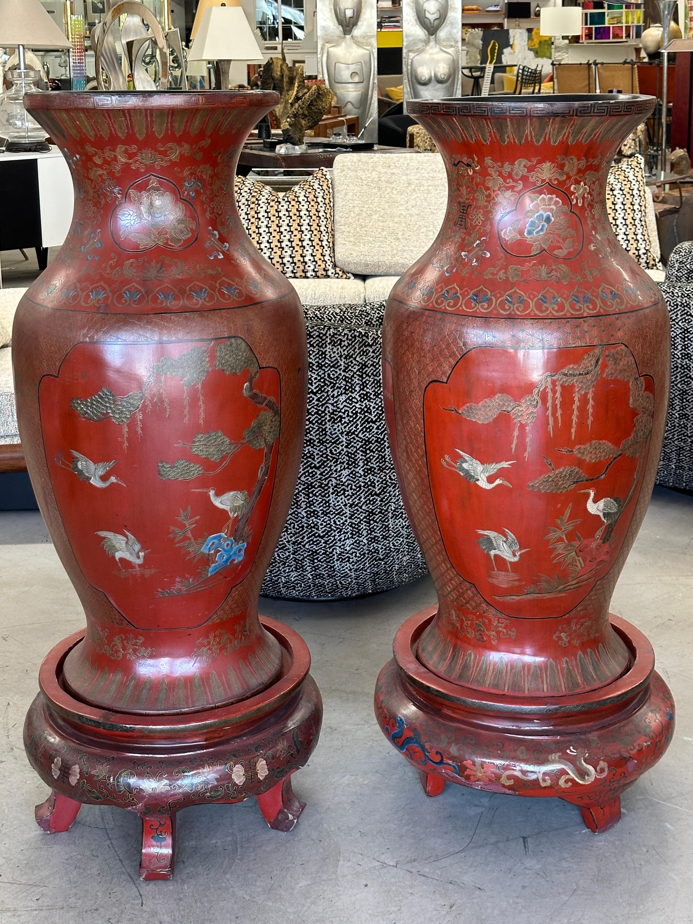 Pareja de monumentales jarrones palaciegos chinos lacados en rojo sobre peanas. Están hechos de madera y papel maché. Hay muchos motivos alrededor de estas grandes piezas, grullas, golondrinas, flores y pájaros  de muchas variedades diferentes.