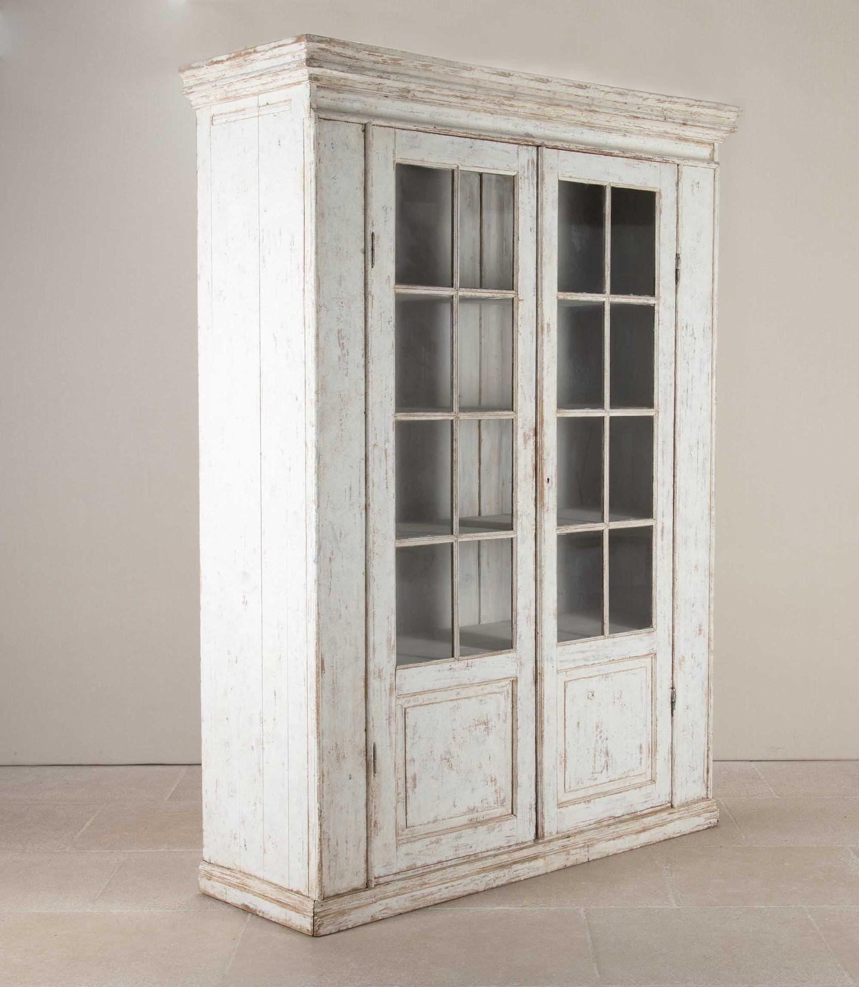 Large 19th Century Continental painted glazed cabinet. The moulded cornice above twin eight pane glazed doors, over inset square fielded panels at the base. Enclosing an arrangement of four fixed shelves, the whole supported on a moulded plinth base.
