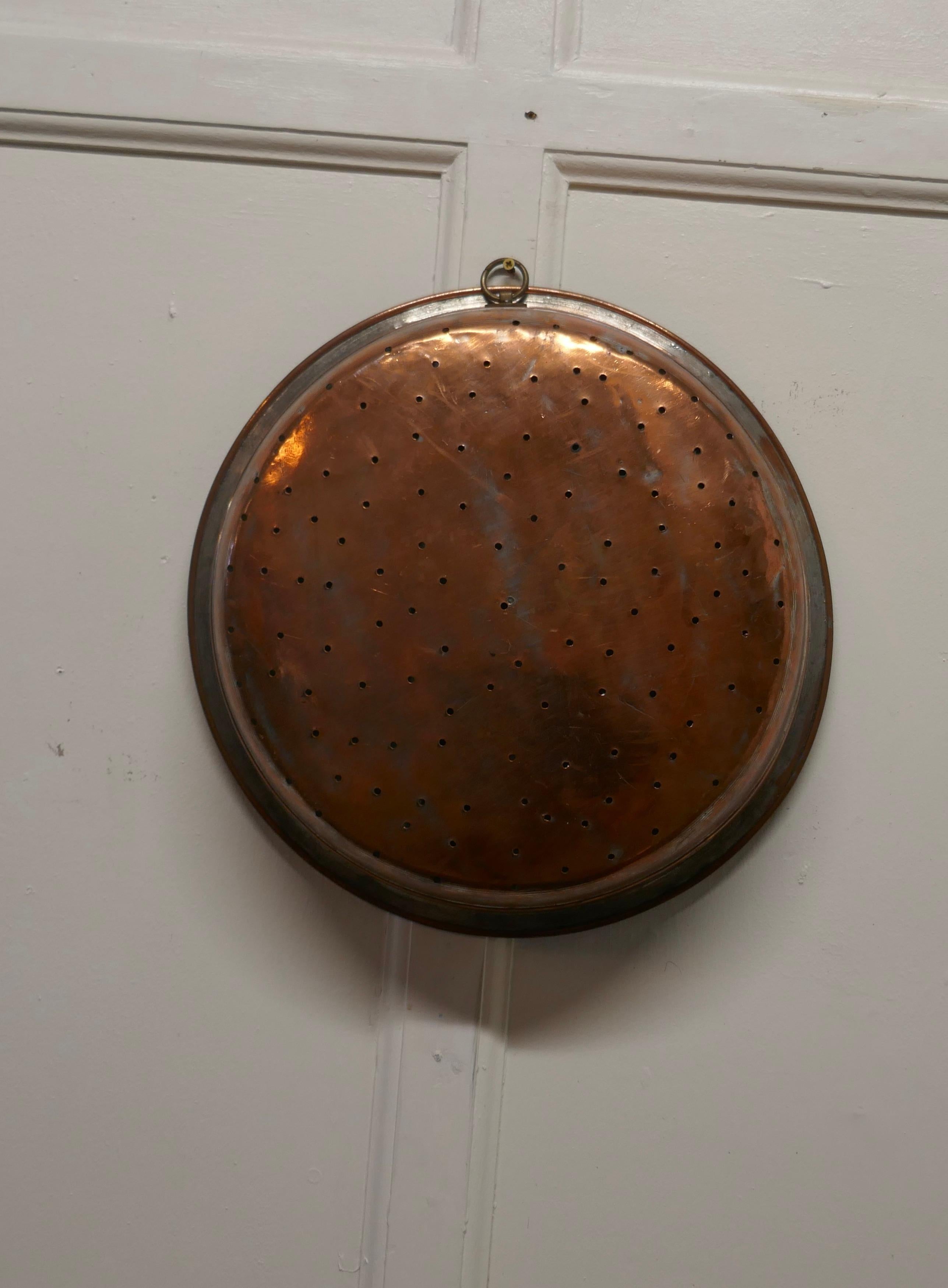 Large 19th Century Copper Draining Dish

This is a lovely looking Georgian Pan, the pan is both a drainer or steamer, it is tinned on the inside and has a ring handle so that it will hang on a wall hook, a lovely piece with a has a charming