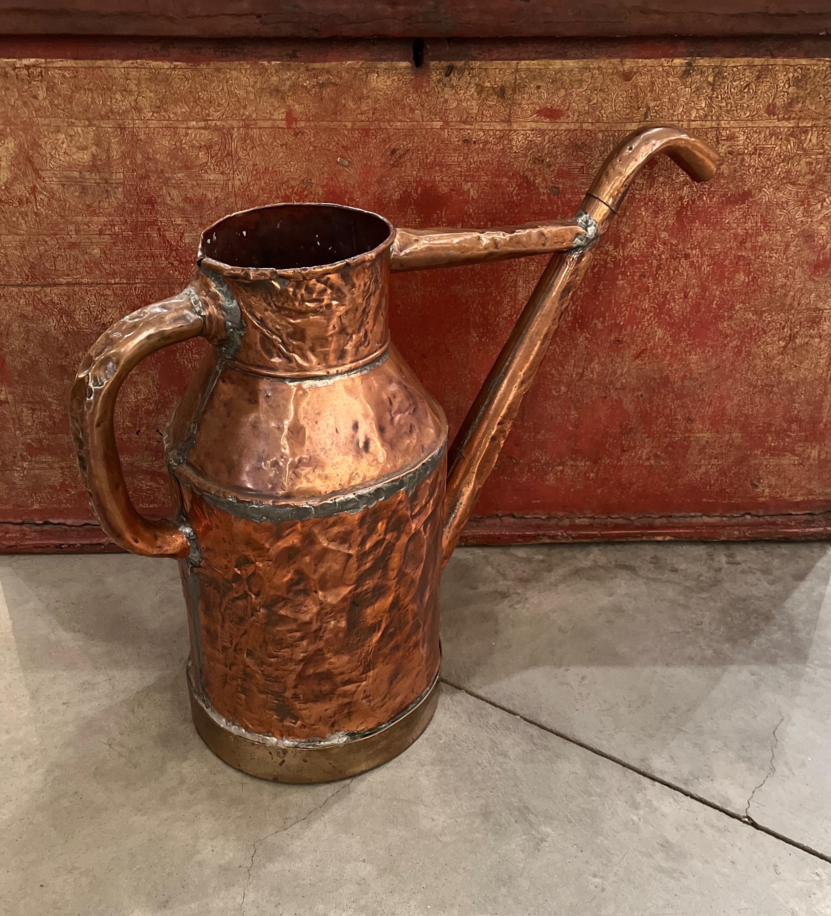 A quite large,  rarely seen hand forged copper oil pitcher, unusual in size and form.  Every small ding and dent speaks to it's frequent use over many decades.  It's evident handmade construction, distinctive patina  and remarkable scale would  make