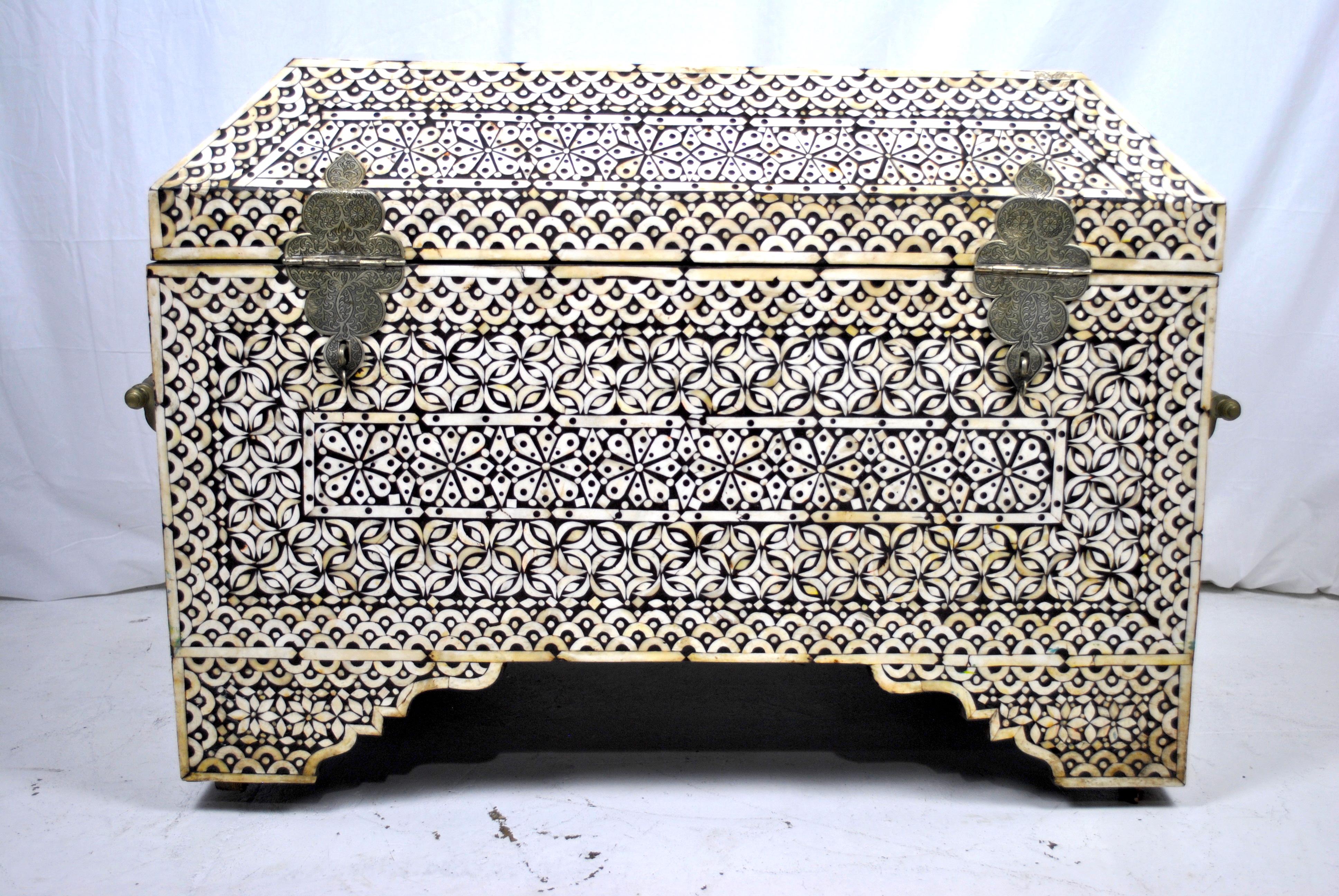 This large 19th century rare Indian ebony and camel bone inlay treasure chest / casket/ box, of rectangular form with hinged lid, scooped tapered feet, silver embossed foliate lock and hinges. The handles are tooled brass. The sides decorated with