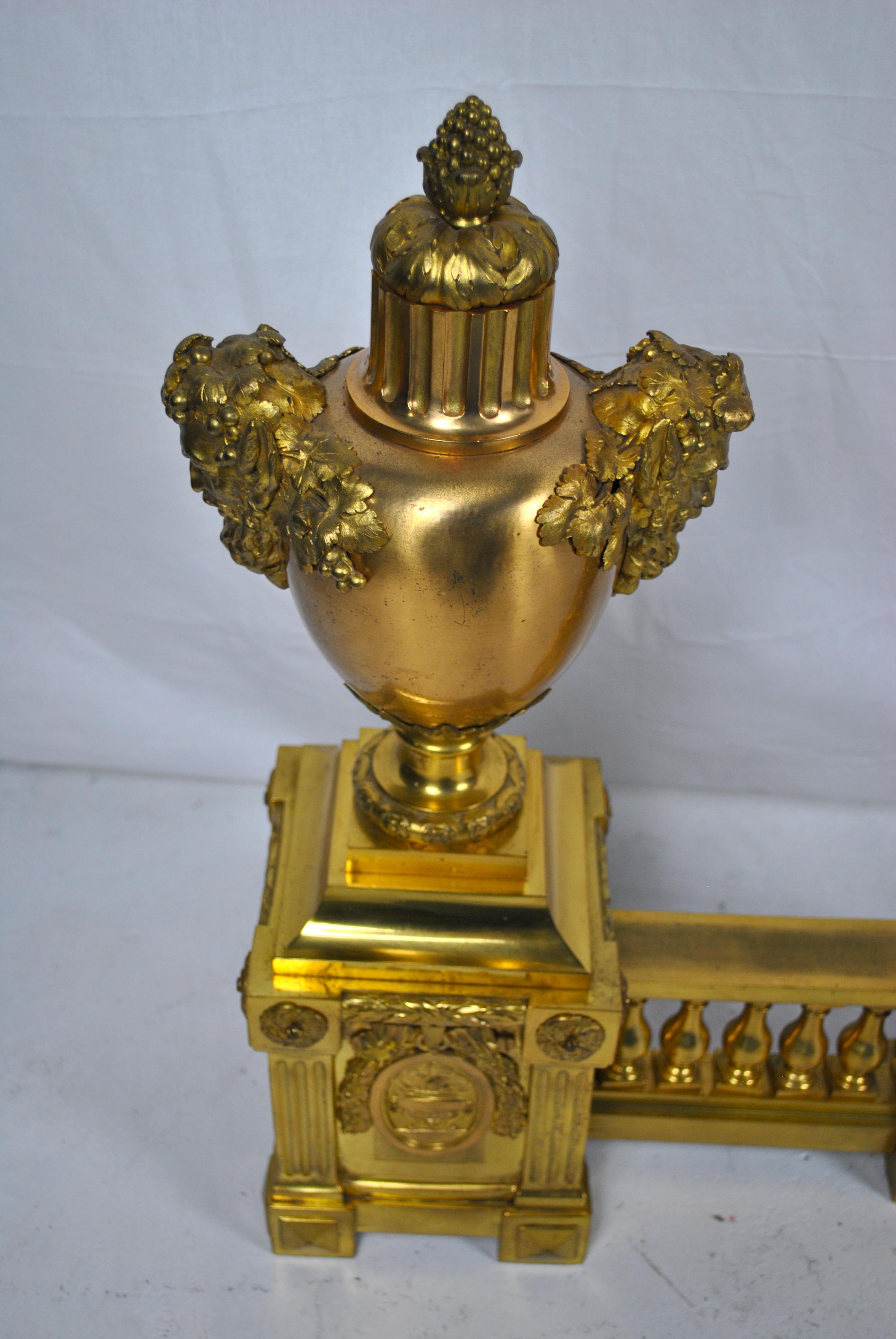 A large elaborate French ormolu on brass fire fender with fire urns in the centre moving to the heads of Bacchus on each side of the outer urns set upon pillars plinths attached to the classic gallery frees and balustrade. Resets attached to each
