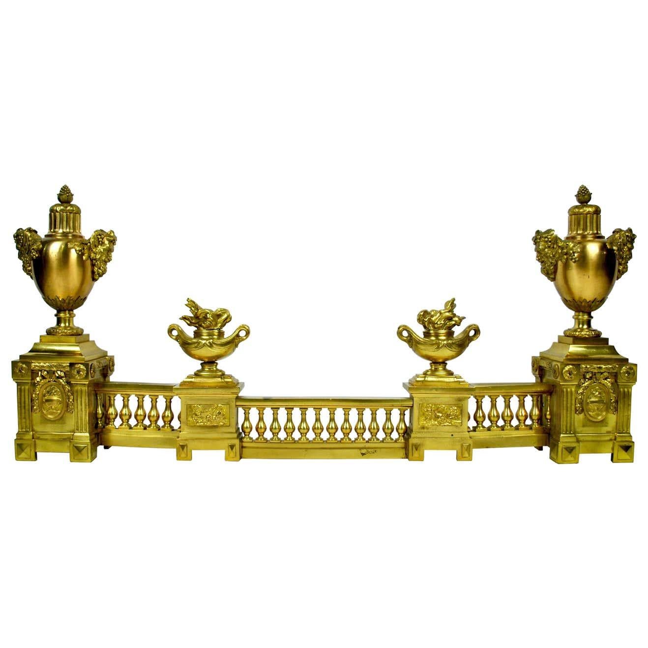 A large elaborate French ormolu on brass fire fender with fire urns in the centre moving to the heads of Bacchus on each side of the outer urns set upon pillars plinths attached to the classic gallery frees and balustrade. Resets attached to each