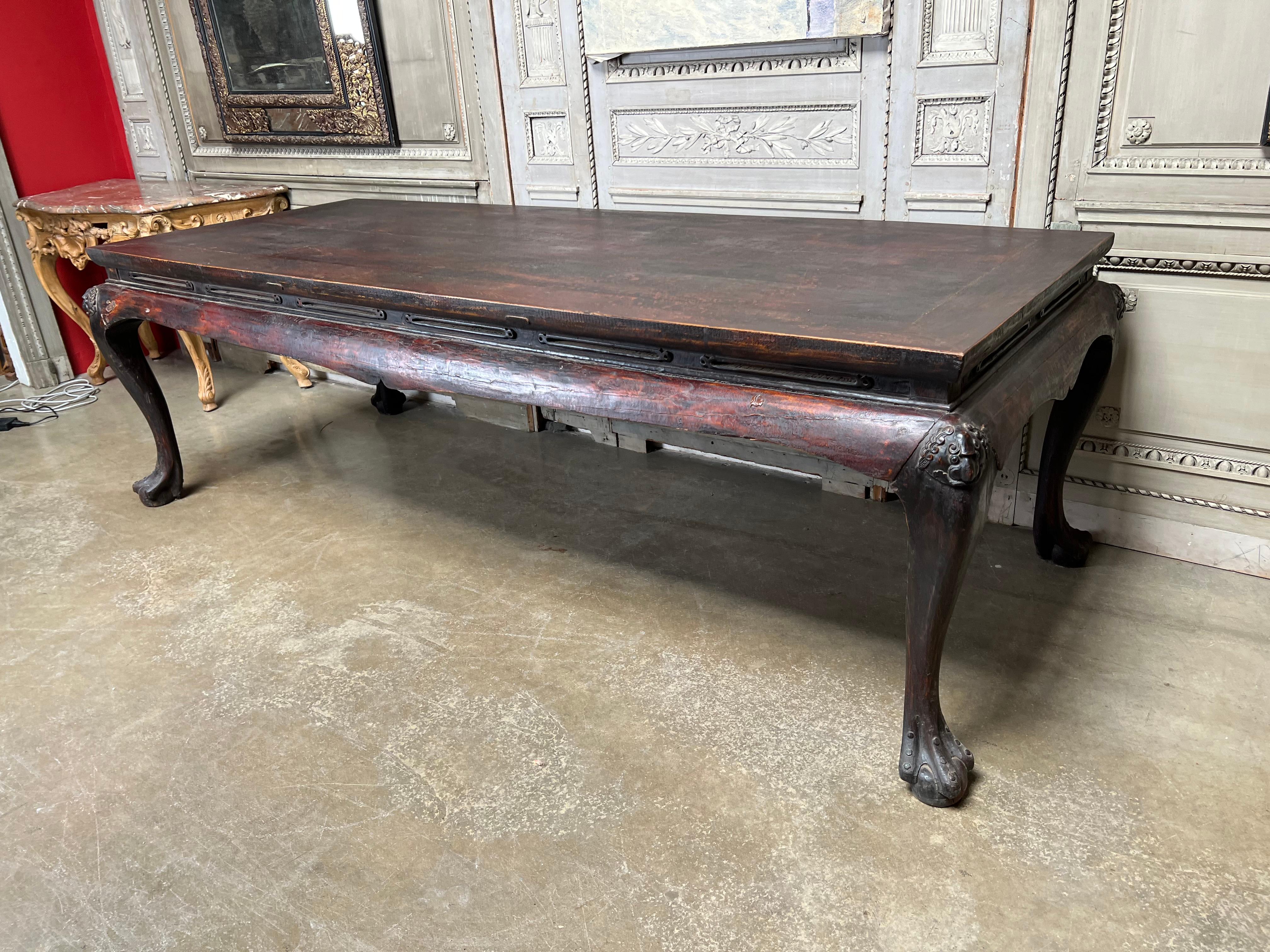 A very large carved and lacquered 19th century elm table from China. This highly decorative table has an old crusty lacquered patina that is beautiful and can be used as a large center table, dining table, kitchen table, work table or conference