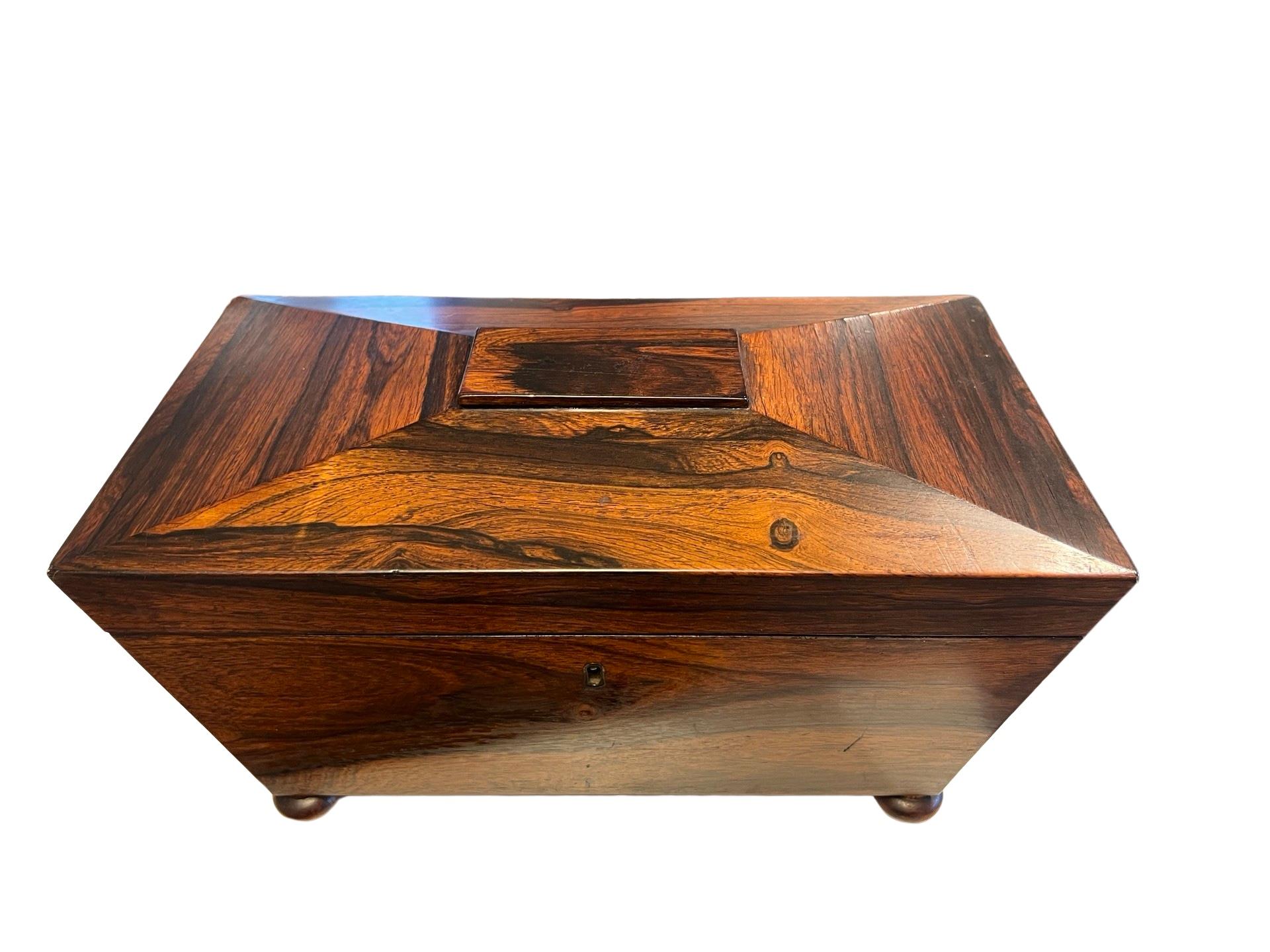 England, circa 1880.

A large sarcophagus form tea caddy box in mahogany. Resting on four bun feet and opens to reveal a tin lined casing, two covered tea sections and a central crystal bowl. 