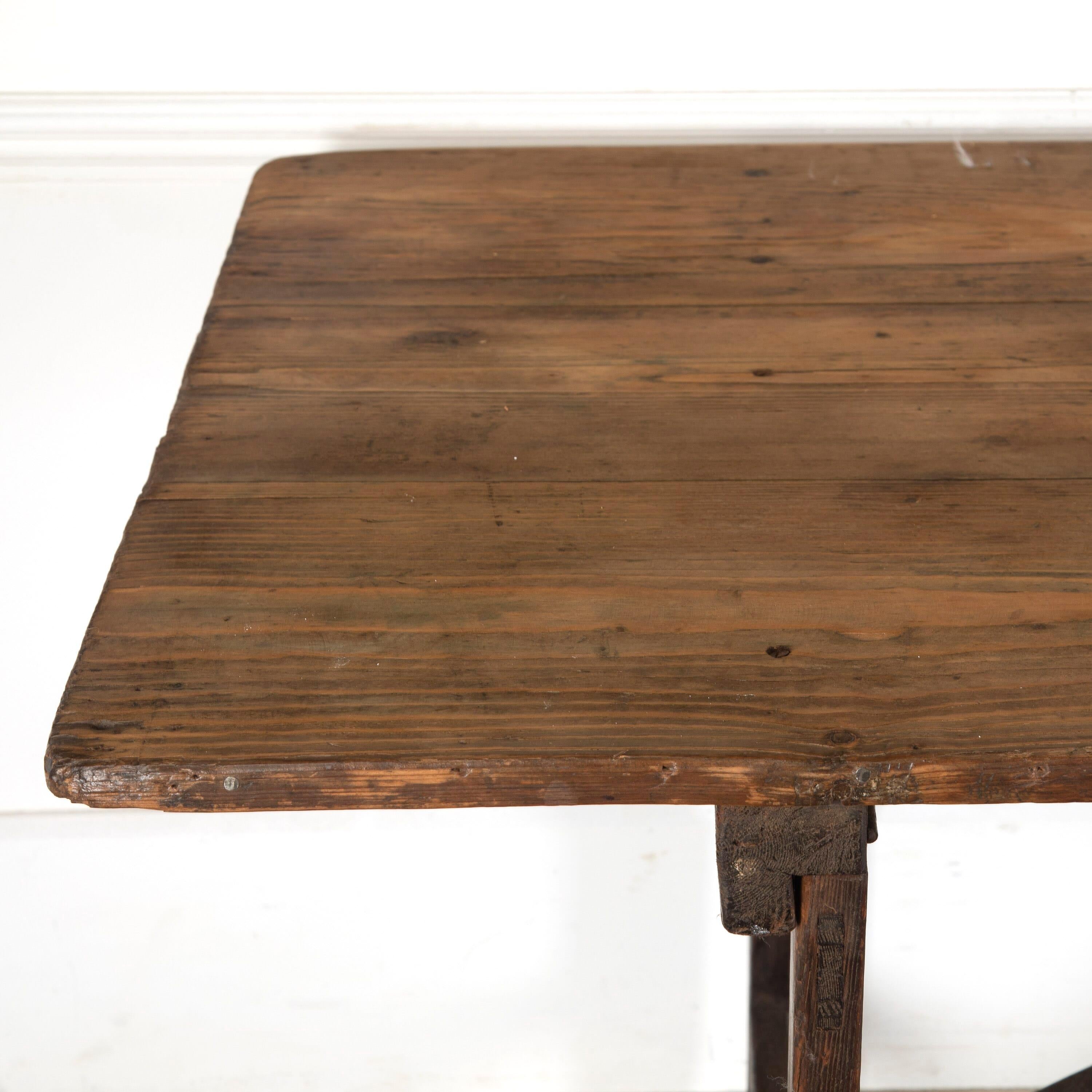 Large 19th century English pine trestle table.

This table features a boarded top with a gorgeous patina, trestle supports, and an attractive vaulted stretcher joining the two ends. 

Of good scale and sturdy, this would make a fantastic dining