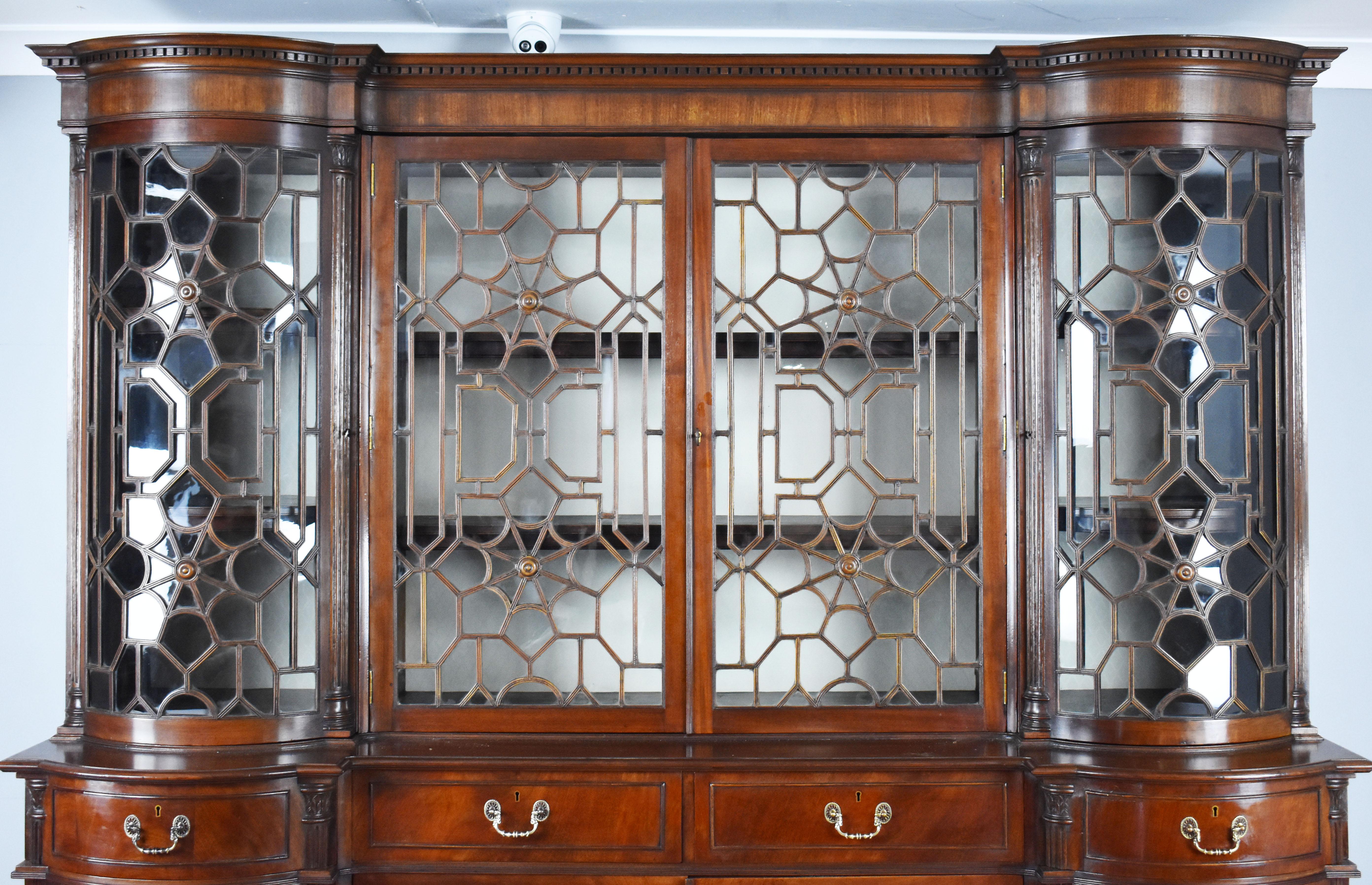 For sale is a fine quality and unusual 19th century English mahogany breakfront bookcase. Having four glazed doors, each with the most ornate glazing bars. The end sections opening to a fabric lined interior complete with adjustable shelves. The