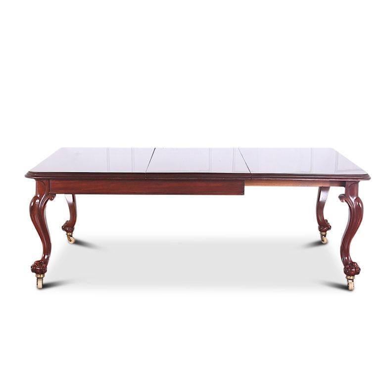 Large 19th century English Victorian solid mahogany dining table with cabriole legs and carved ball-and-claw feet with the original porcelain casters. Included is one leaf to extend up to 7 feet long; the table will further extend to take more