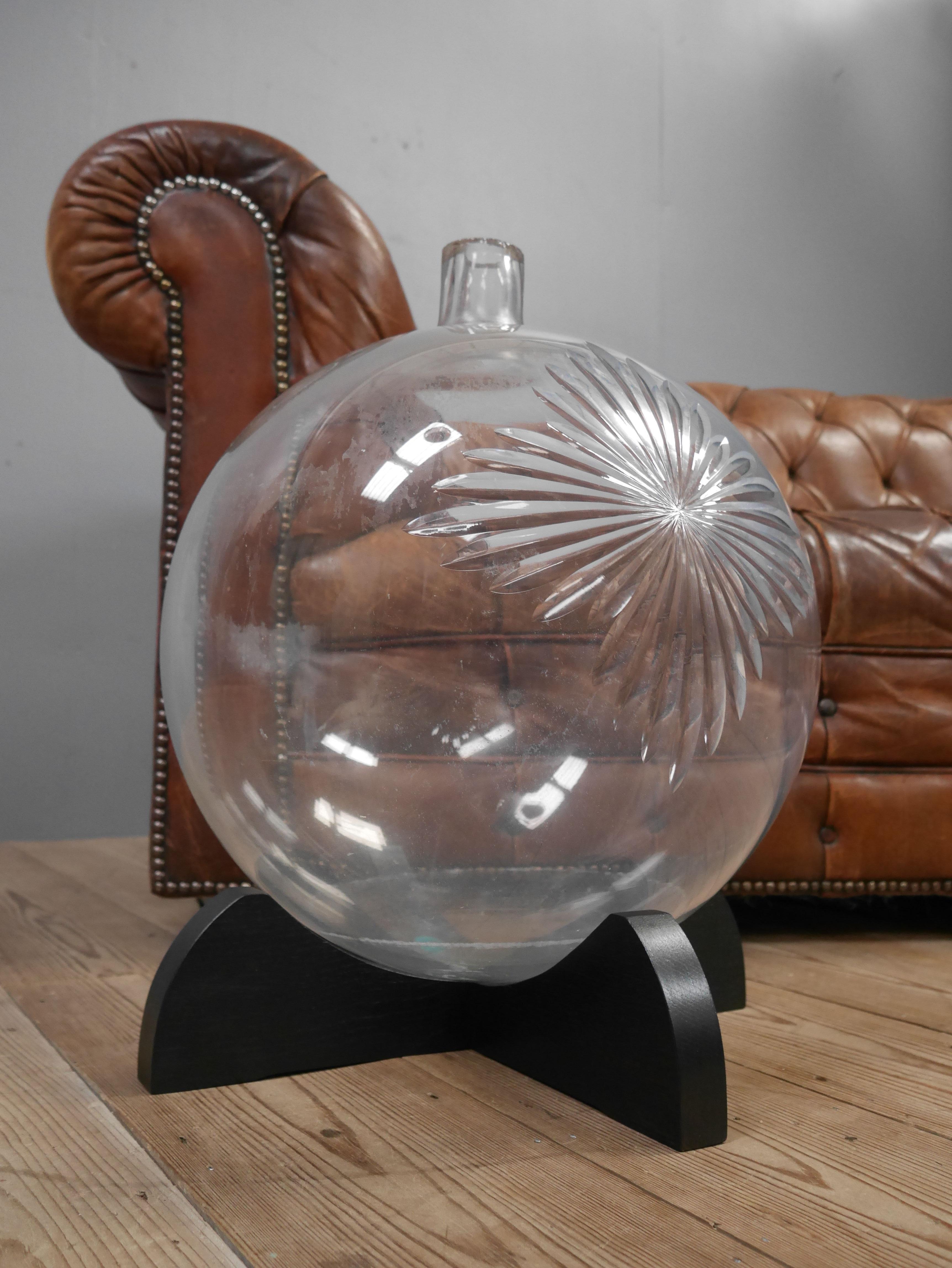 A large antique glass chemists advertising carboy.
A beautiful & exceptionally rare chemist's carboy, hand blown in thick glass, on an ebonised oak stand & finished with a large wheel cut star to the front, a representation of the pharmaceutical
