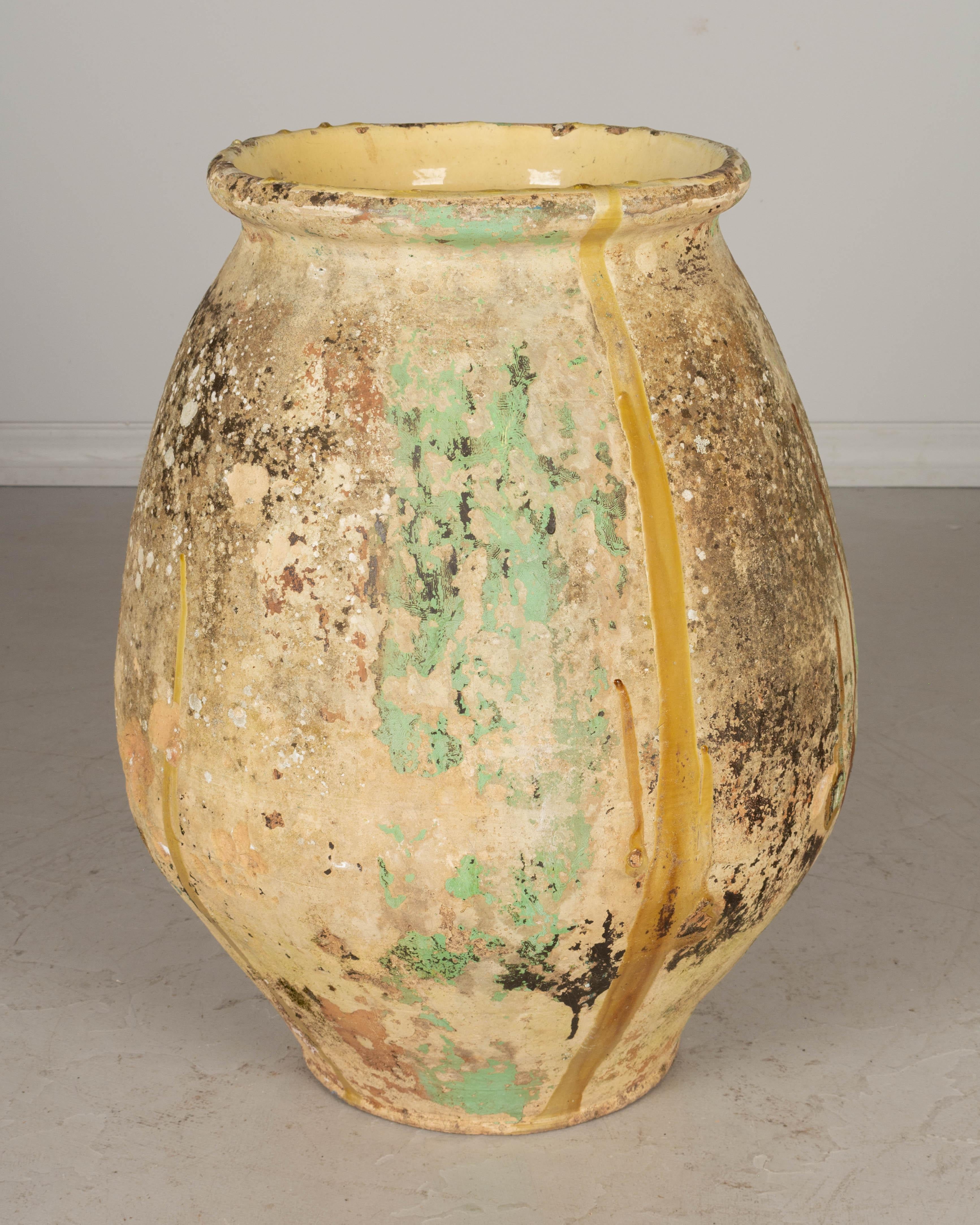 A large early 19th century French terracotta pottery Biot jar in classic shape and having a lovely aged patina with remnants of old green and yellow ochre drip glaze. Hand formed using the ancient technique of rope thrown pottery, these jars were