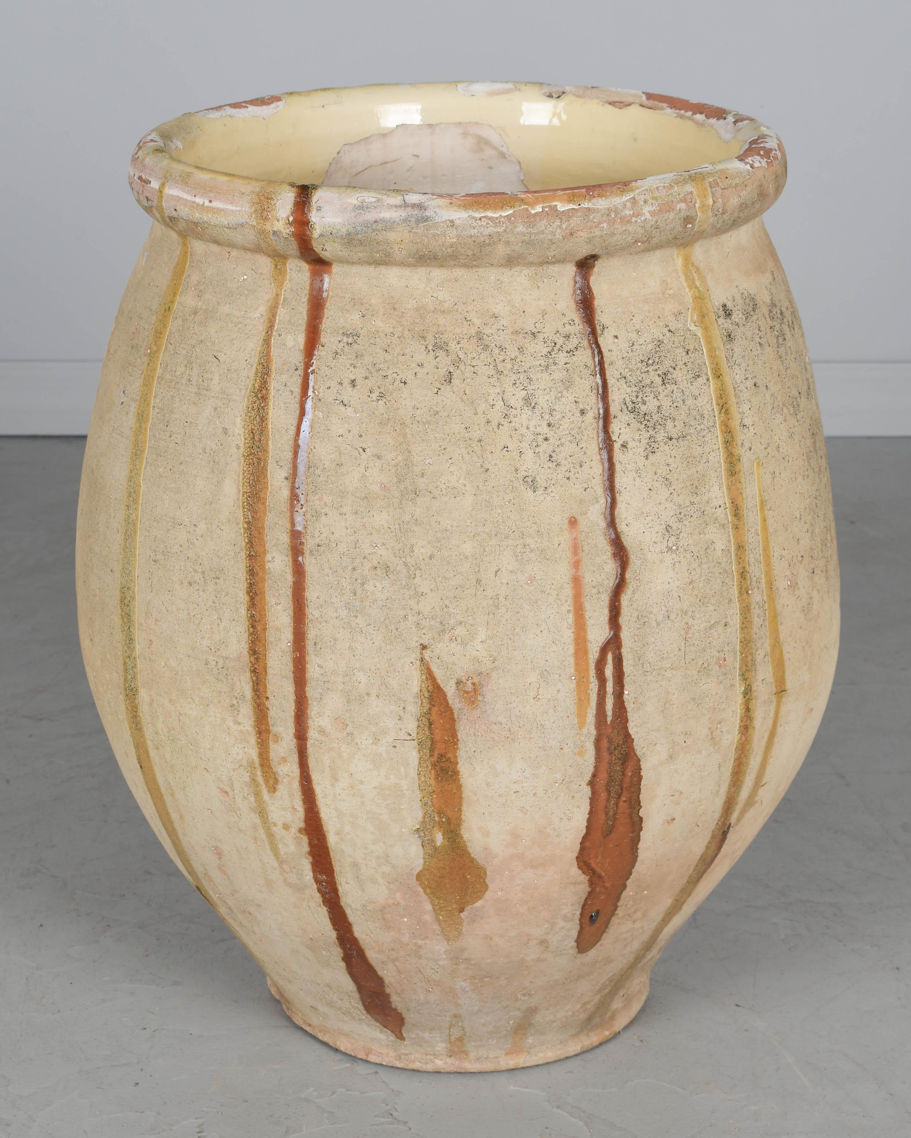 A large early 19th century French terracotta pottery Biot jar in classic shape with aged patina and a few large drips of ochre glaze. Interior and rim have pale yellow glaze with minor losses. Hand formed using the ancient technique of rope thrown