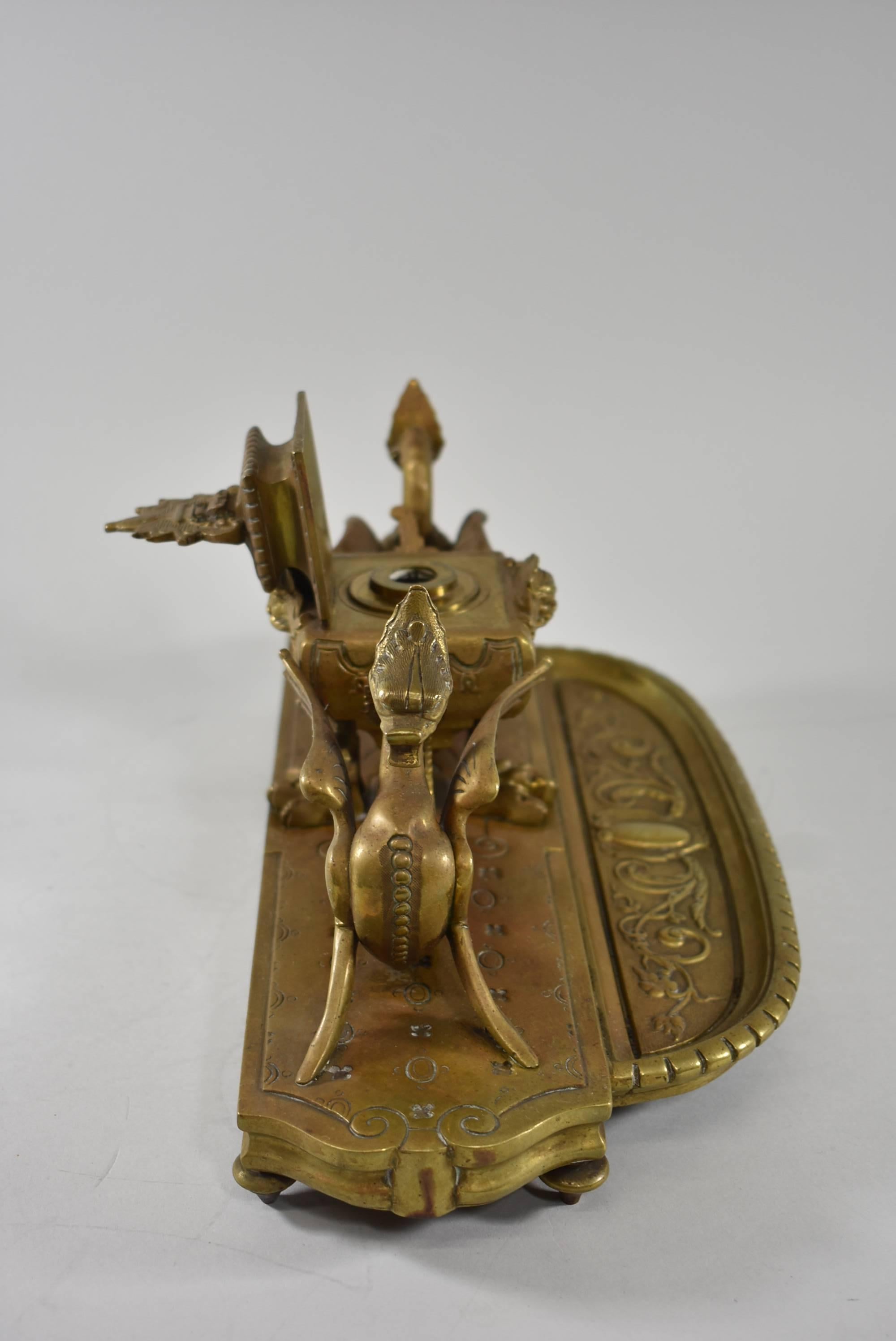 A beautiful large and heavy bronze inkwell. This inkwell features gorgeous detailing with dual guard dragons with serpent tails and the well has faces with griffin claw feet. The pen tray on the front is decorated with beautifully embossed scrolling