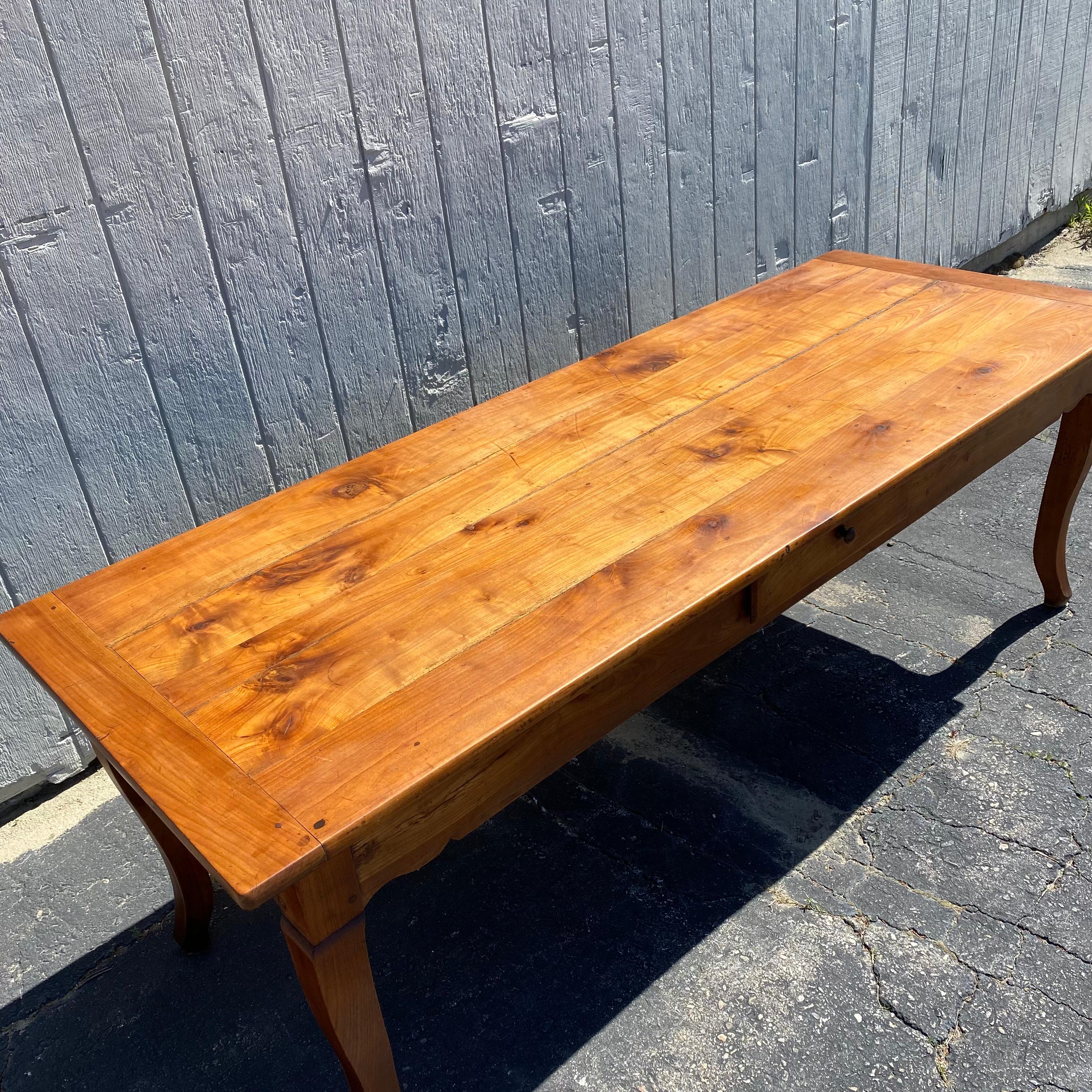 French provincial cherry farmhouse table with graceful cabriole legs, single center drawer, shaped skirt all around, and two breadboard leaves on either end of the table that extend to make the table 10 feet long. This early 19th century table was