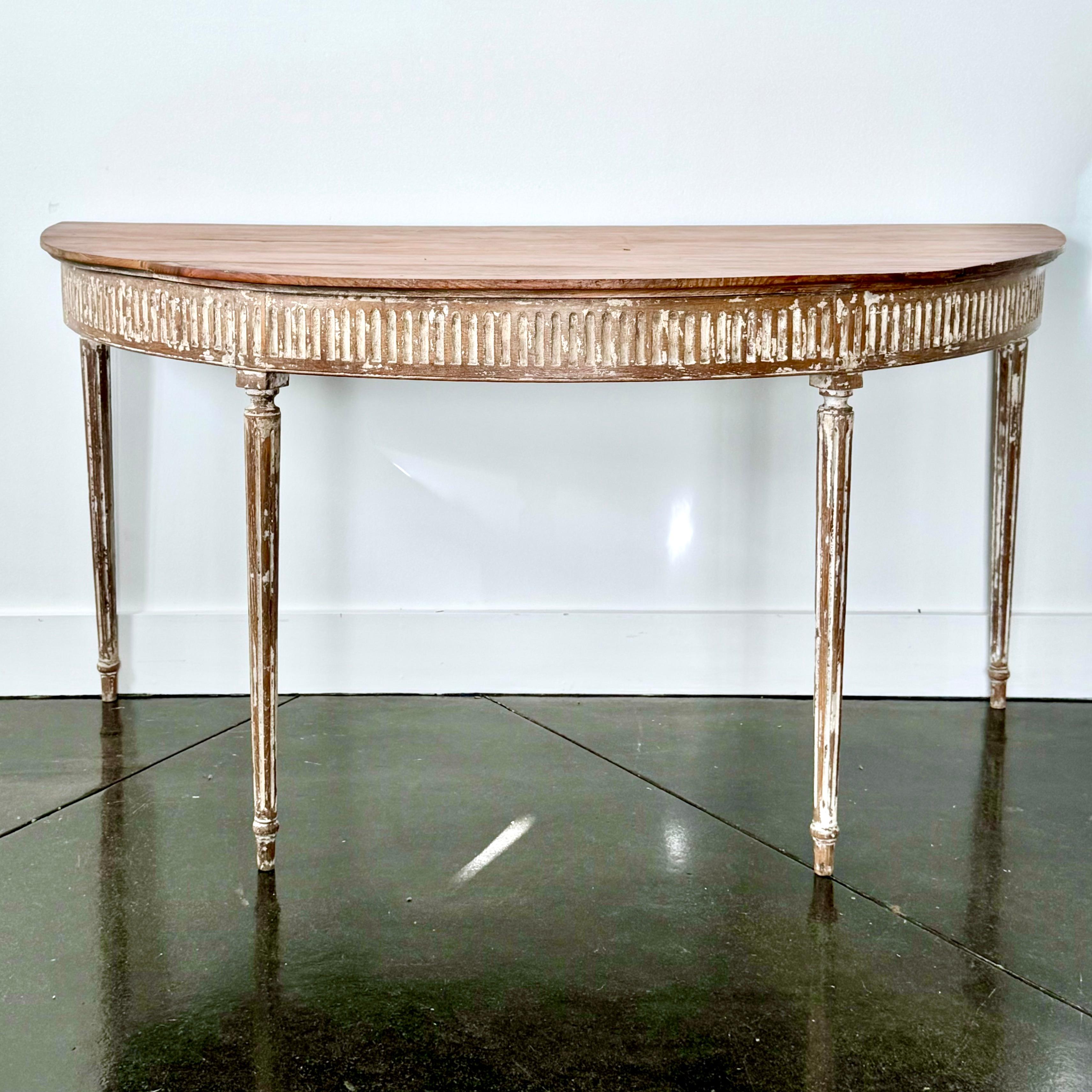 Classic, large 19th century French Louis XVI style console table in carved wood, with remnants of old white paint. The elegant console with fluted carved frieze and plaster shaped tapered legs.