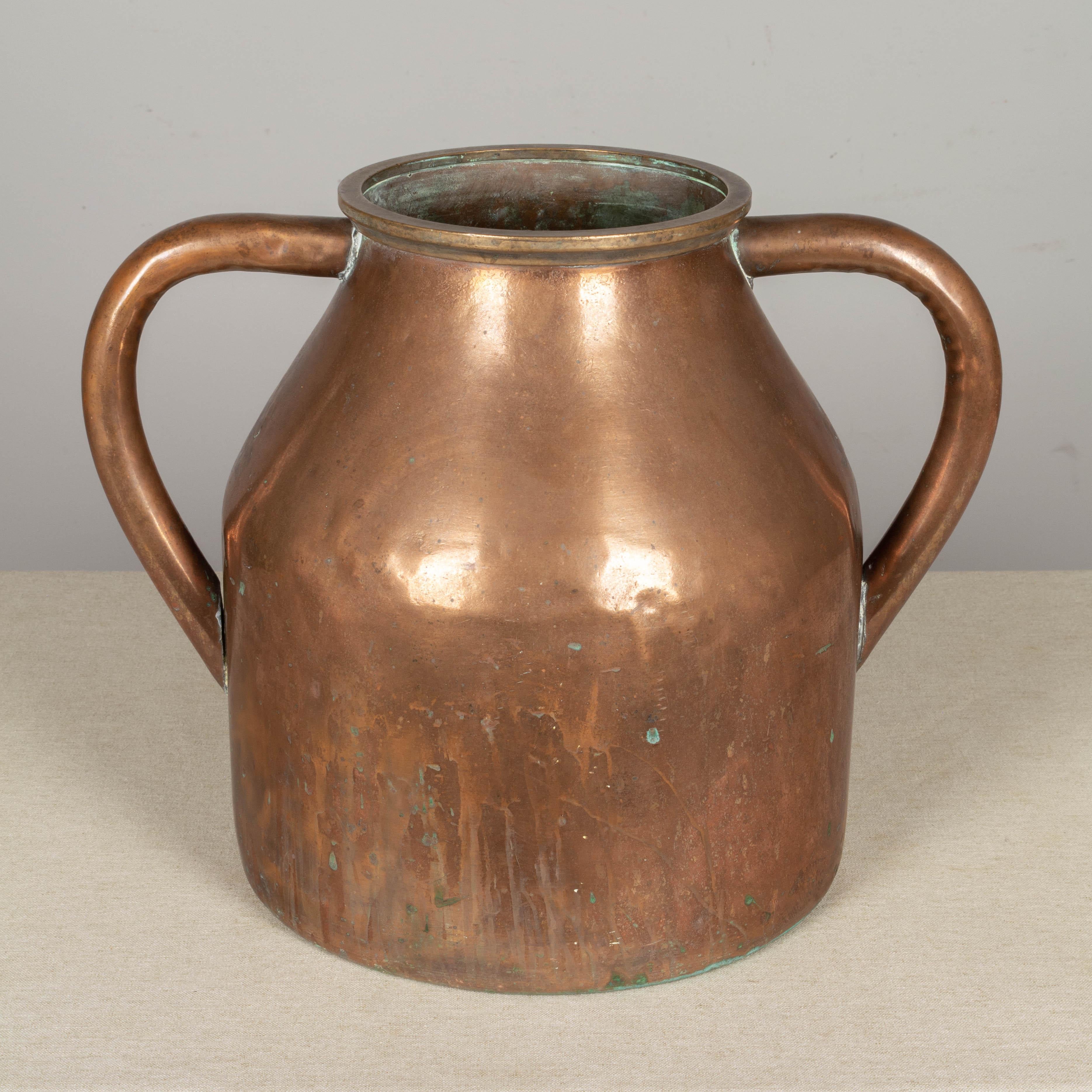 A large 19th century French copper vessel or vase with double handles. Beautiful warm patina with streaks and green oxidation. 
Overall dimensions: 14