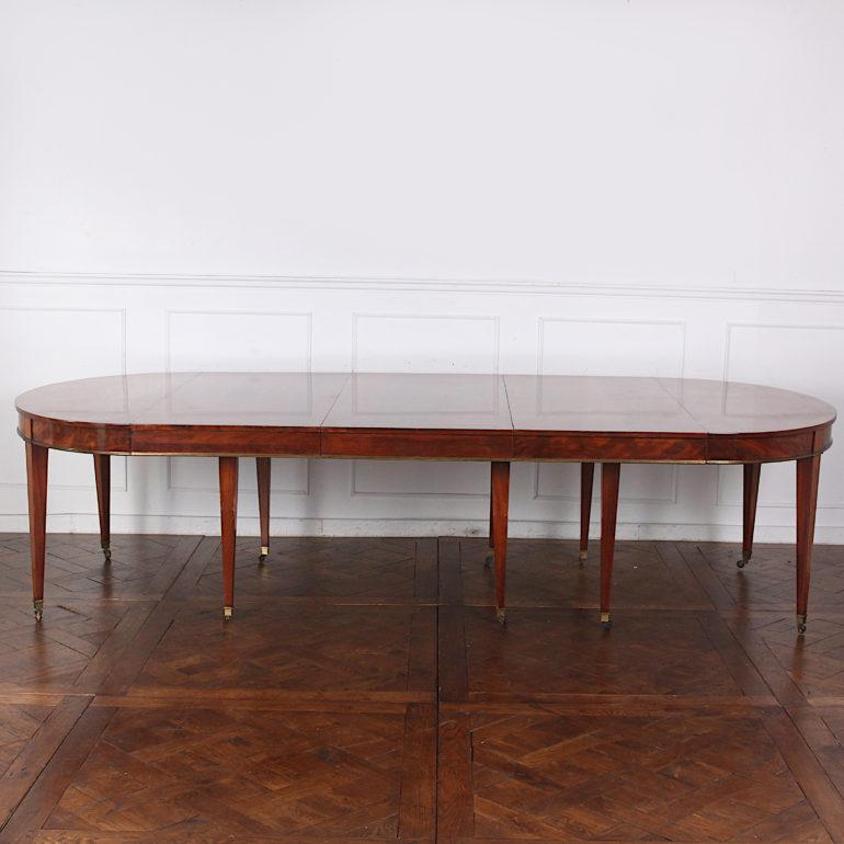 An unusually-large French Directoire style mahogany dining table with three leaves, one skirted and two without skirts. Raised on square-tapering legs with brass castors.

Measures: 90? wide x 52? deep x 28.5? tall (closed  skirted leaf is 24?