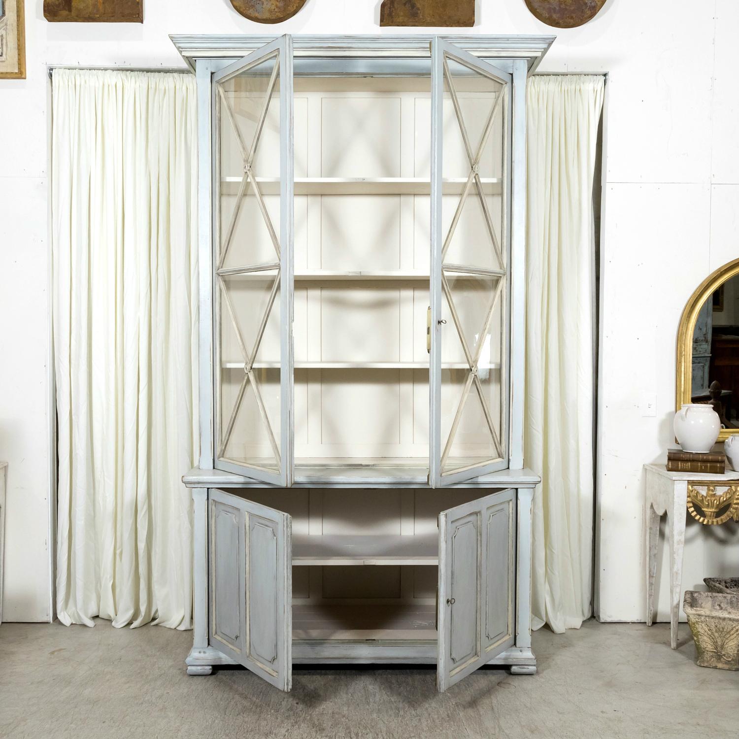 This exceptional mid-19th century French Directoire period painted bookcase or display cabinet from Gordes, circa early 1800s, embodies the elegance and craftsmanship of its era. Handcrafted by skilled artisans in the renowned Provençal city of
