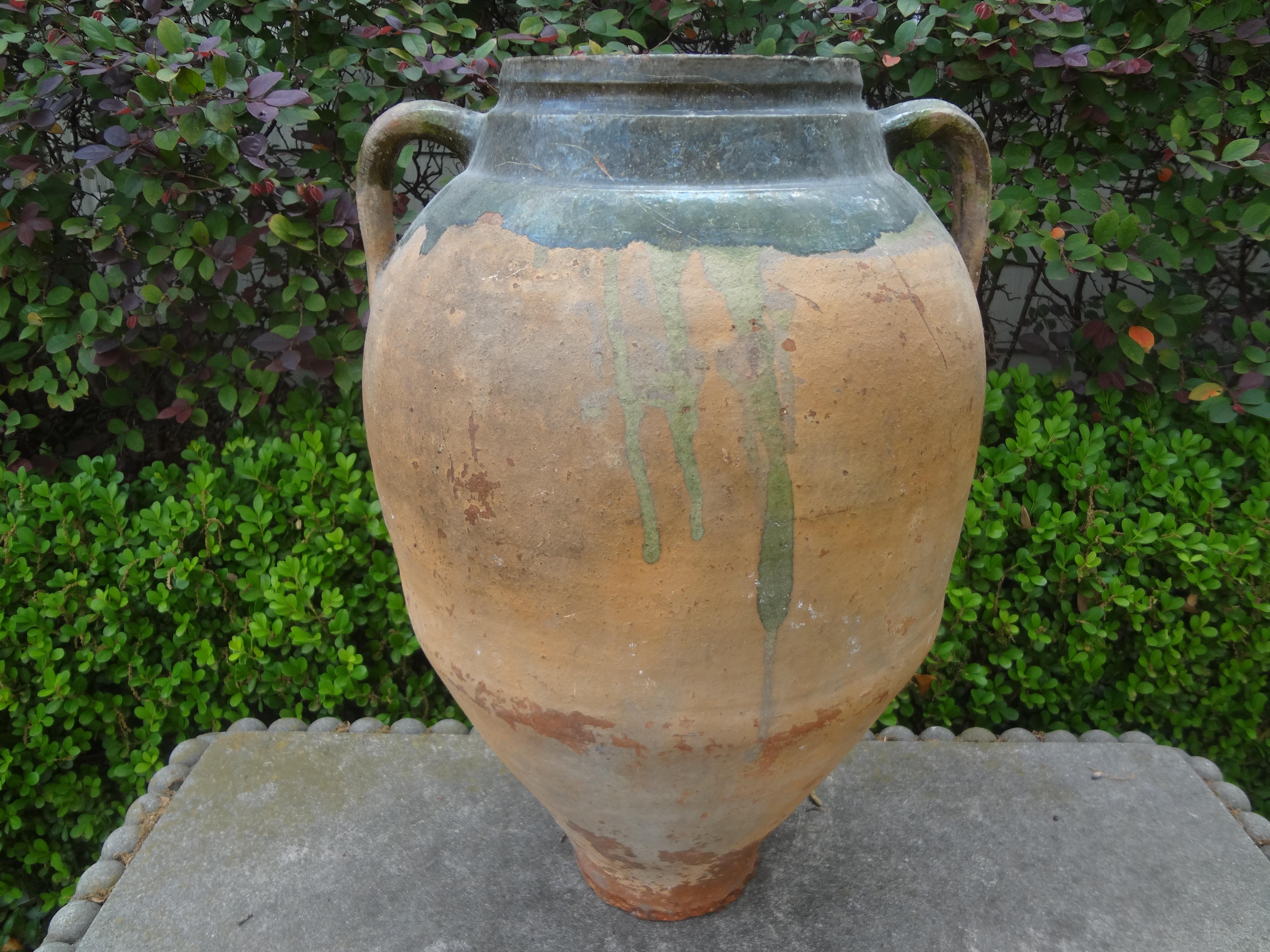 Large 19th century French earthenware vessel.
This handsome antique French Provincial earthenware, pottery or terra cotta urn or vessel with handles was originally used for storing olives or olive oil and is now a beautiful decorative