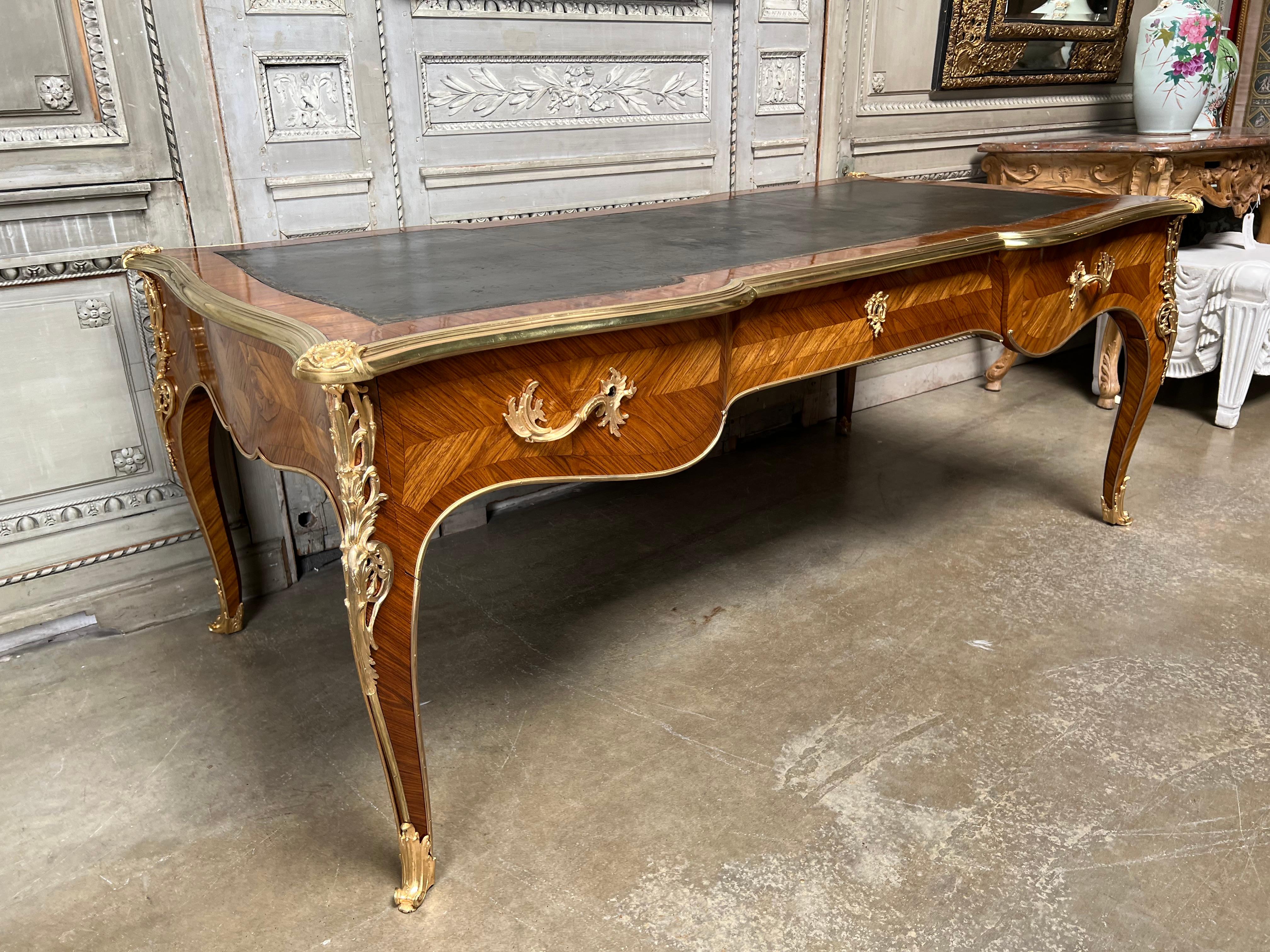 A very large French Louis XV style bureau plat partners desk from the late 19th century with an old black leather tooled top. This desk is beautifully veneered in kingwood and rosewood and is mounted in ormalu and polished bronze. There are three