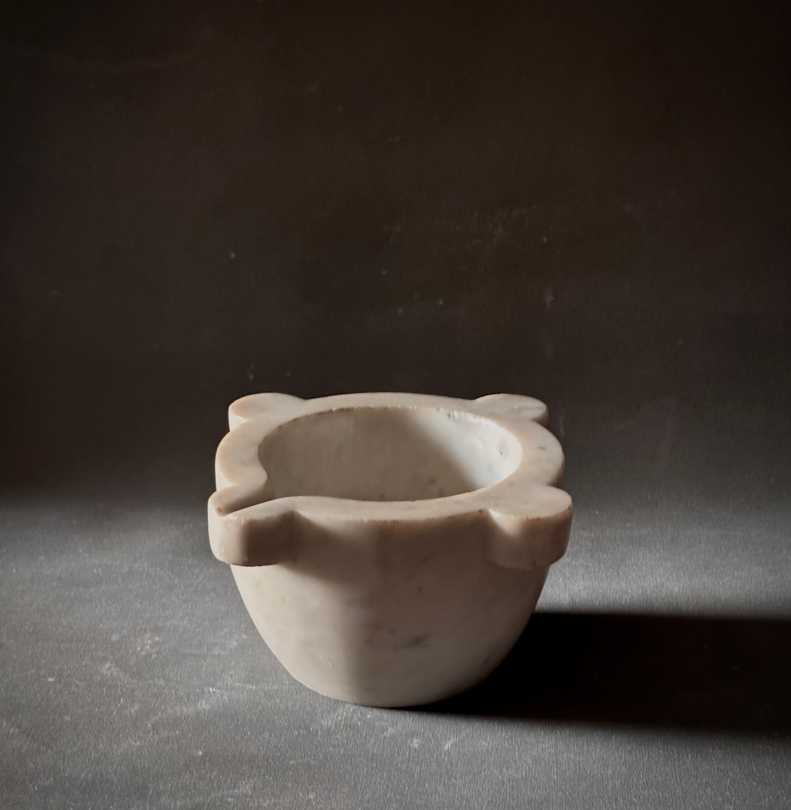 Scolpito in marmo bianco incontaminato, questo mortaio francese del XIX secolo sposa l'utilità e l'eleganza. Il pezzo presenta una base conica graziosamente affusolata ed è accentuato da quattro manici dentellati in demi-lune, che offrono un fascino
