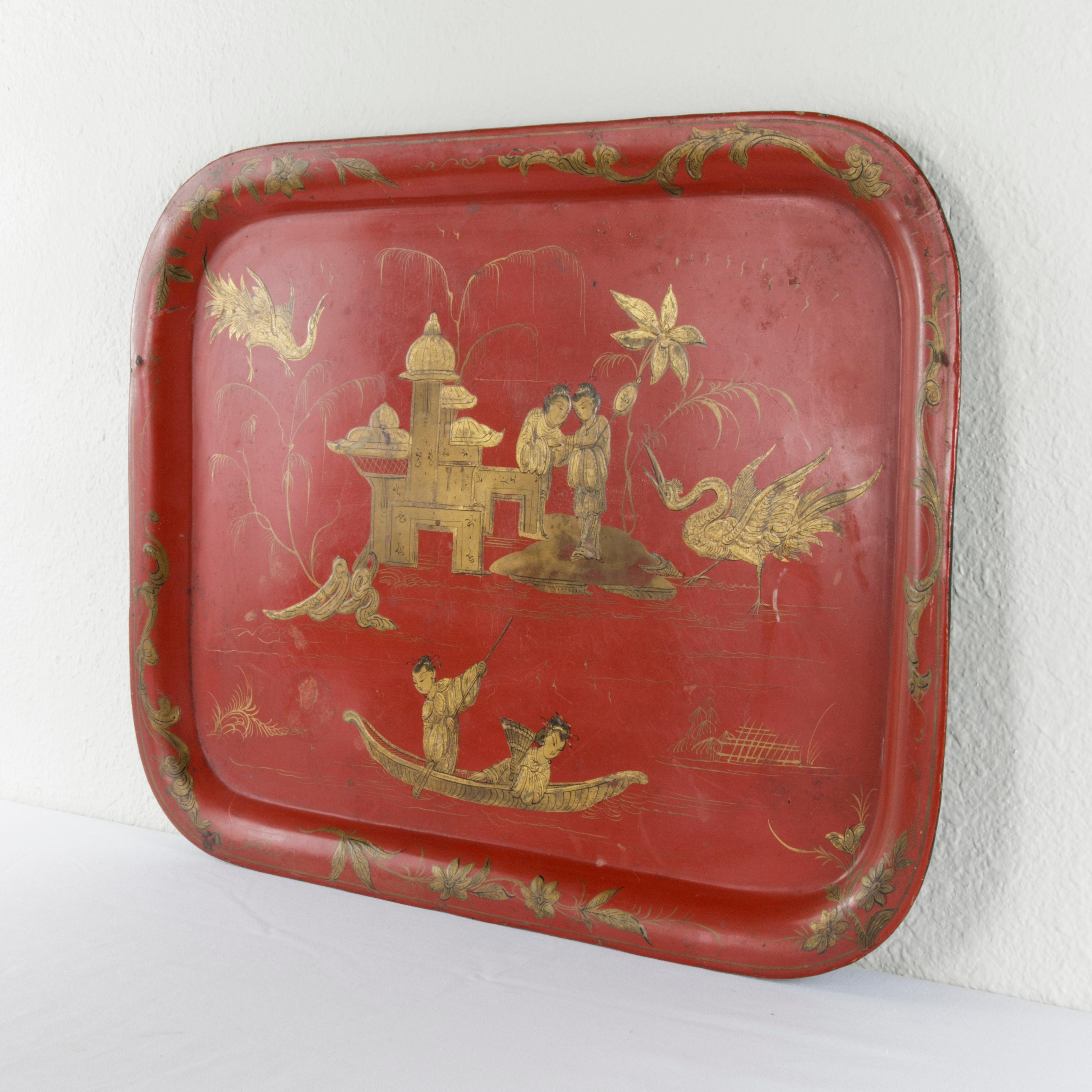 This very large French Napoleon III period red tole metal tray from the late 19th century features beautifully hand painted gold chinoiserie. This imagery from the Far East became popular during the reign of Napoleon III. Displayed in the middle of