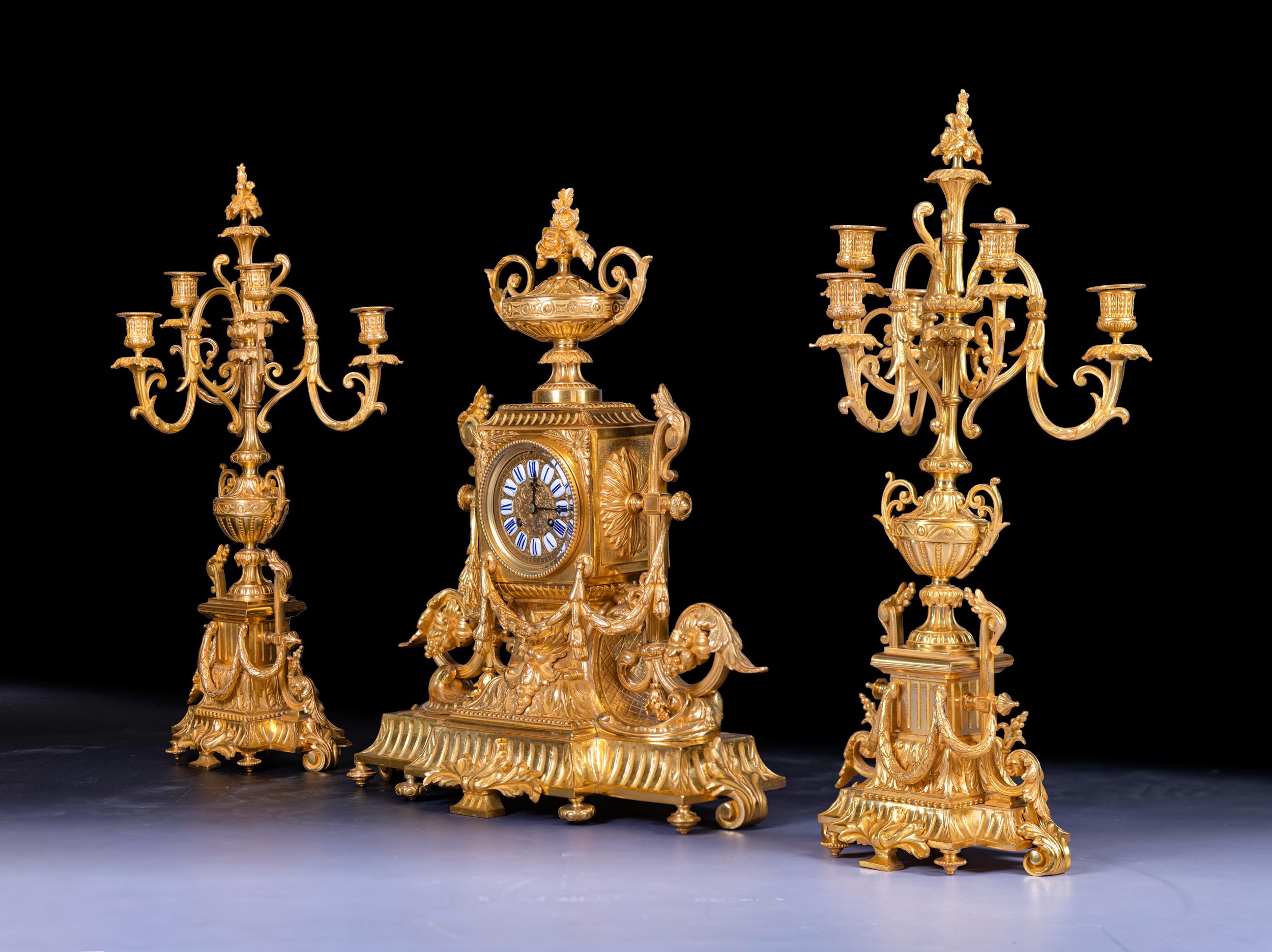 Measures: H: 25 1/2 in / 64.7 cm ; W: 22 1/4 in / 56.5 cm ; D: 9 1/2 in / 24.2 cm

An exceptional quality three-piece clock set designed in a grand neoclassical.
The set is comprised of a central clock and two flanking candelabra. The clock