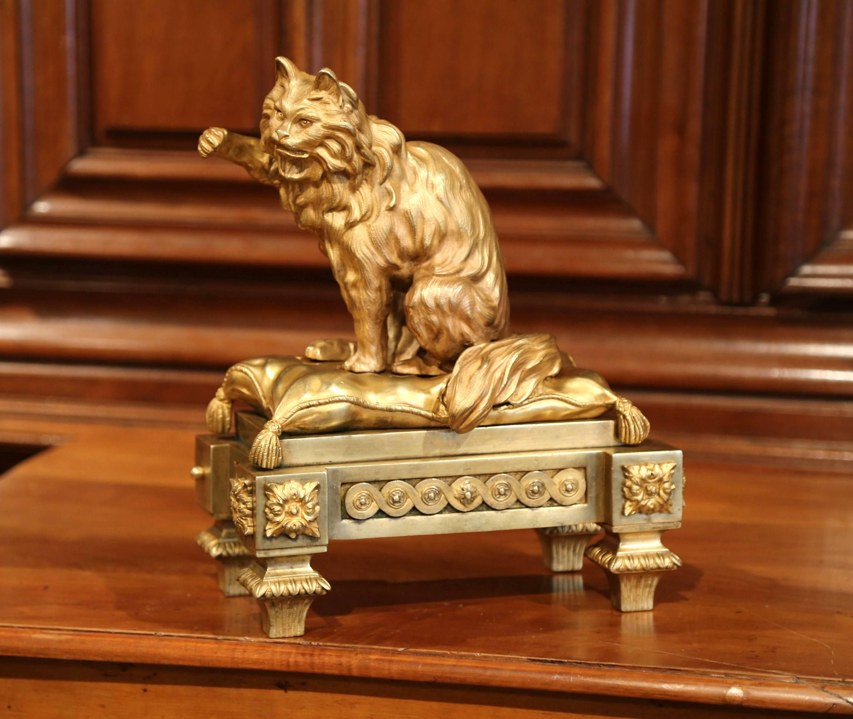 Decorate a shelf in a study with this elegant antique cat bronze sculpture from France. Crafted circa 1840, the feline figure sits on a pillow with his right paw up. The bronze cat sculpture is situated on an ornate base with four small tapered feet