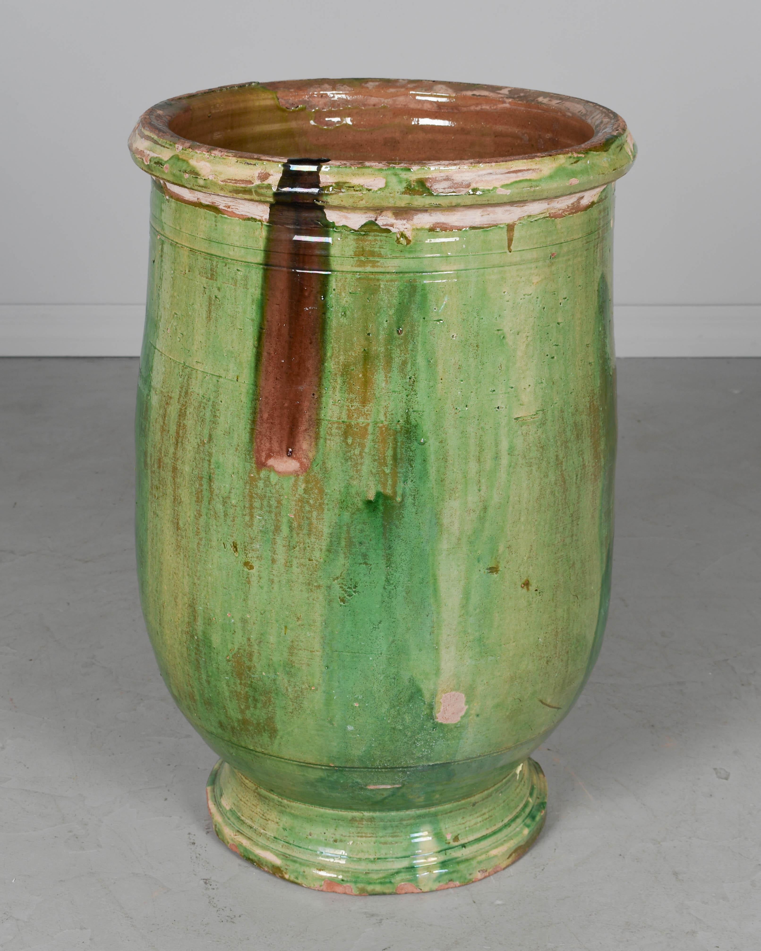 A large 19th century green glazed terracotta pottery olive oil jar from the Southwest of France. Minor losses to glaze and chipped rim. A beautiful garden ornament, fountain, or planter for indoor or outdoor use. We have a selection of large French