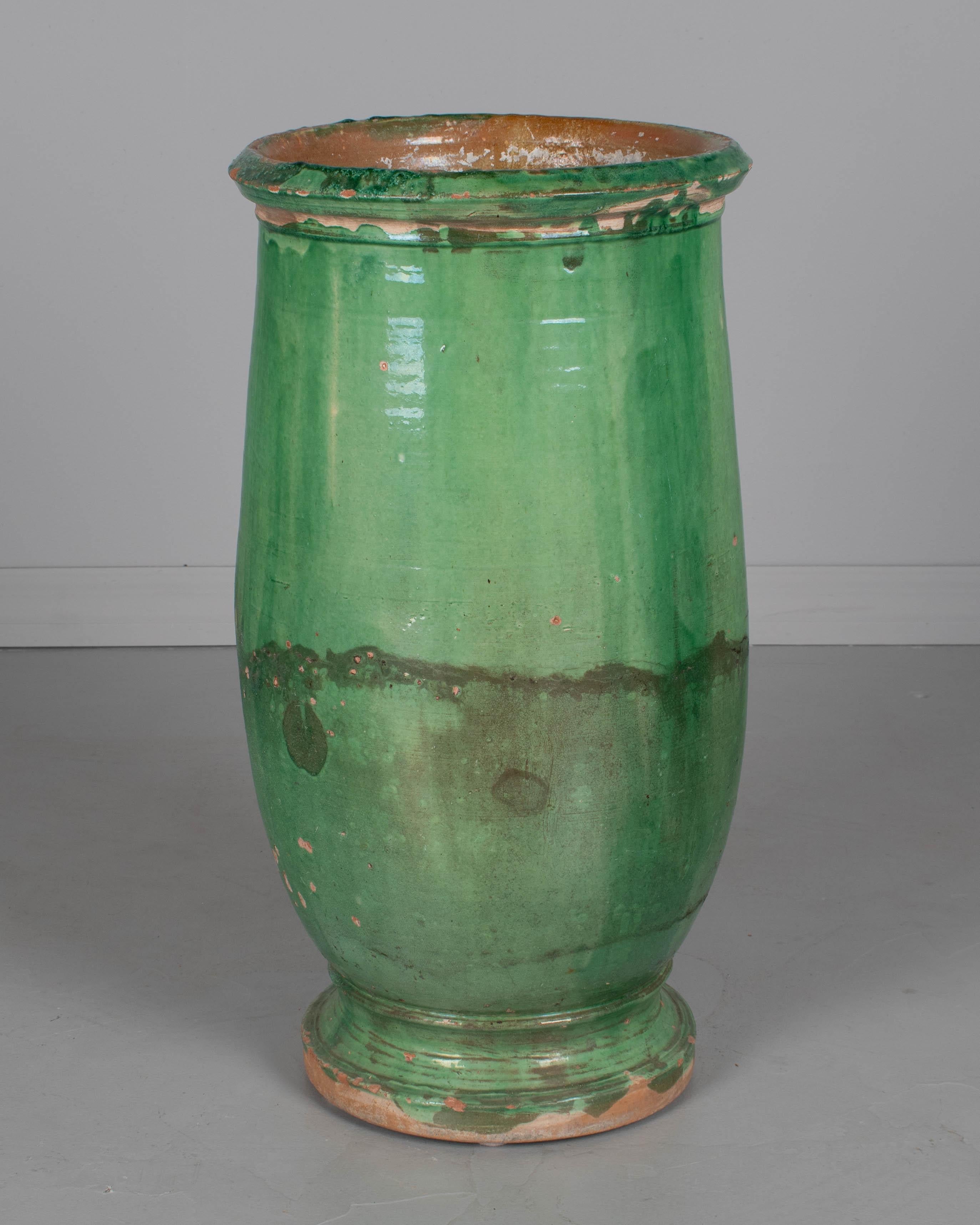 Grande jarre à huile d'olive en terre cuite vernissée verte du 19e siècle, originaire du Sud-Ouest de la France. Petites pertes de glaçure et bord ébréché. Un bel ornement de jardin, une fontaine ou une jardinière pour l'intérieur ou l'extérieur.