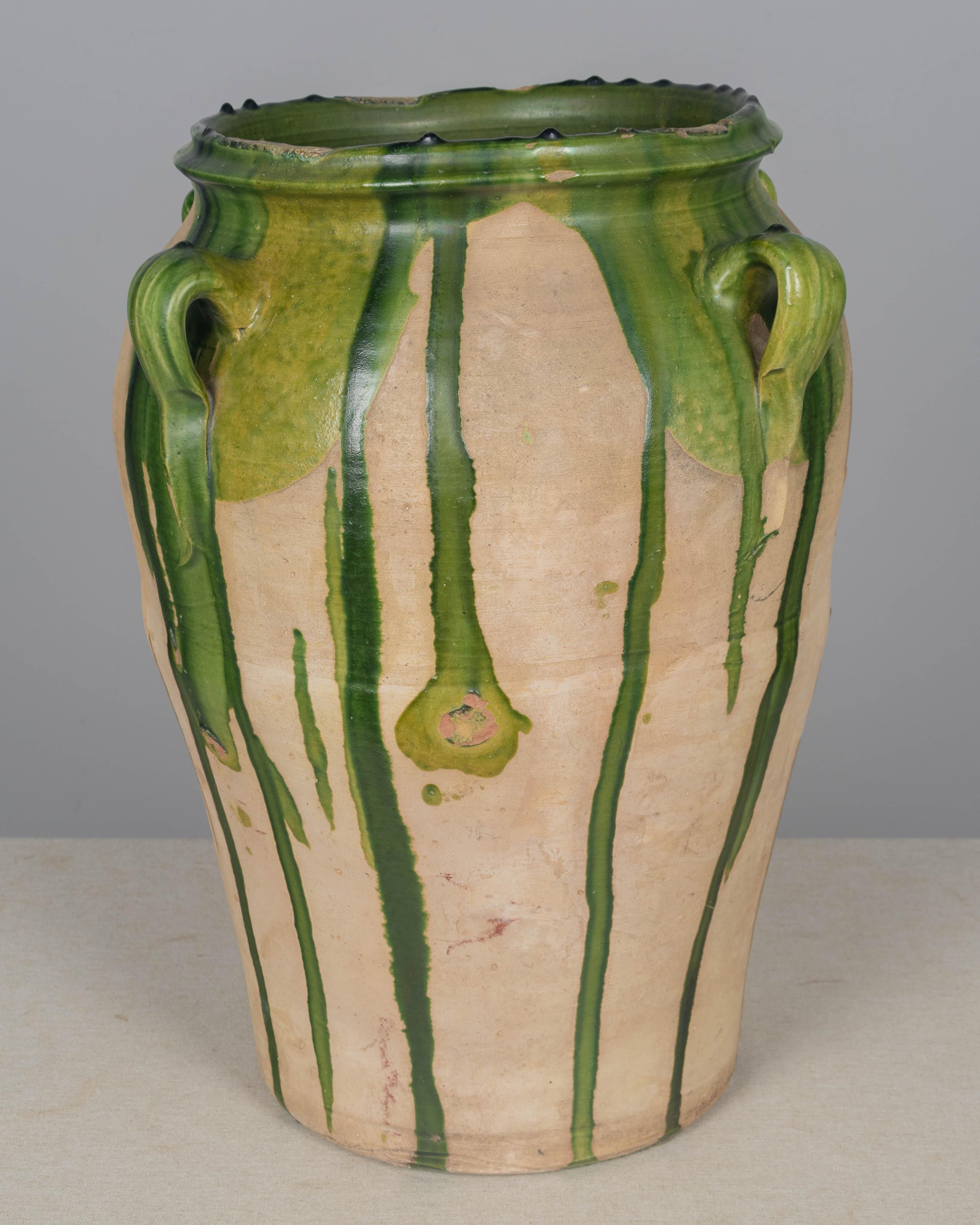 A large 19th century terracotta pottery olive oil jar with green drip glaze from the Southwest of France. Minor losses to glaze and some chips. A beautiful garden planter or floor vase for indoor or outdoor use. We have a selection of large French