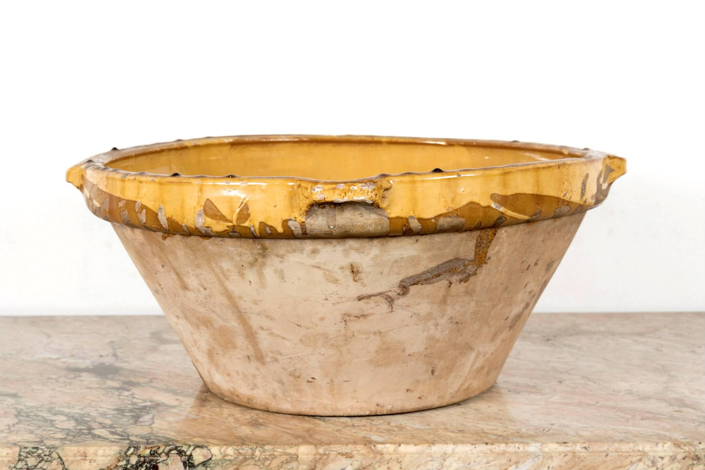Lovely 19th century French terracotta bowl, known as a tian, once used to prepare and cook boudin noir or cassoulet. This round handmade terracotta bowl from southwest France features two small handles, a lip for pouring, and has a Provencal yellow
