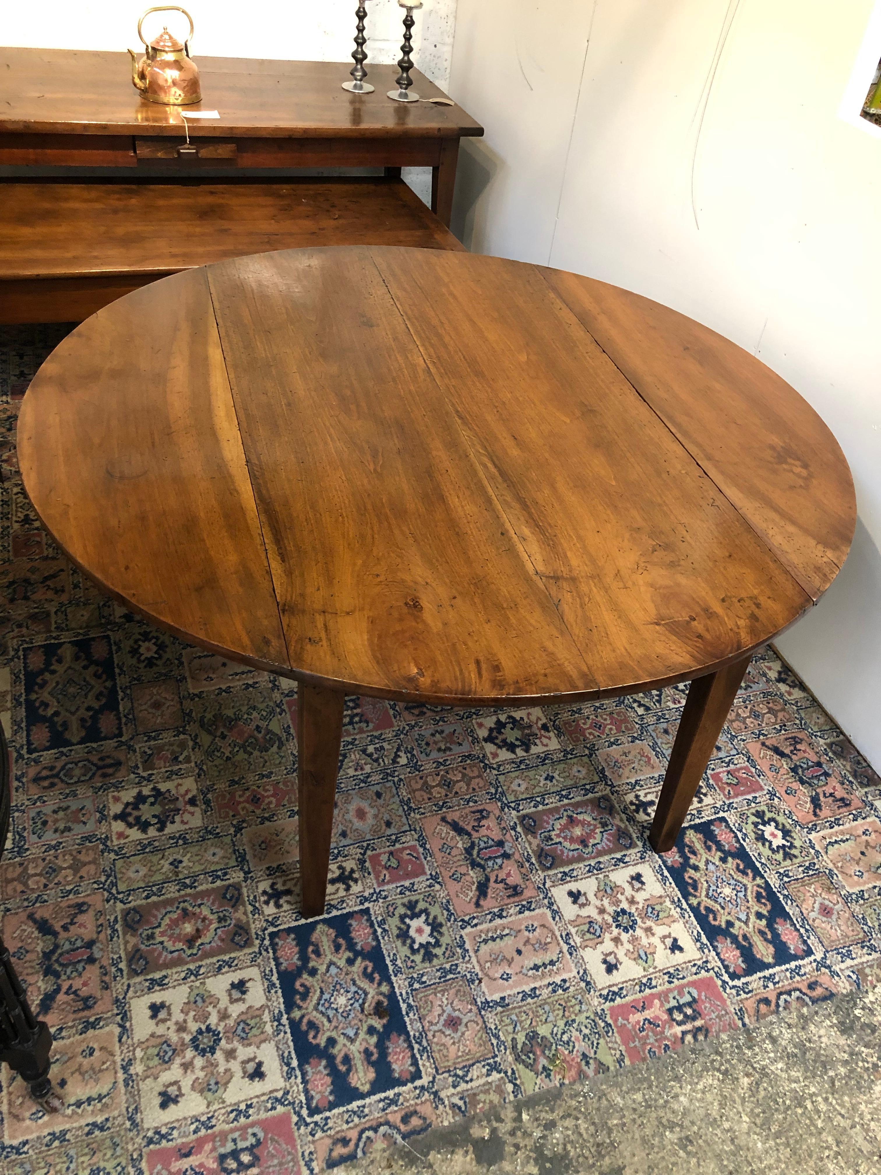 A large sturdy French beautifully figured solid walnut drop leaf circular dining table. The drop leaves having a sliding bar mechanism on the underside of the table to hold them firmly in place when extended. In completely original condition.