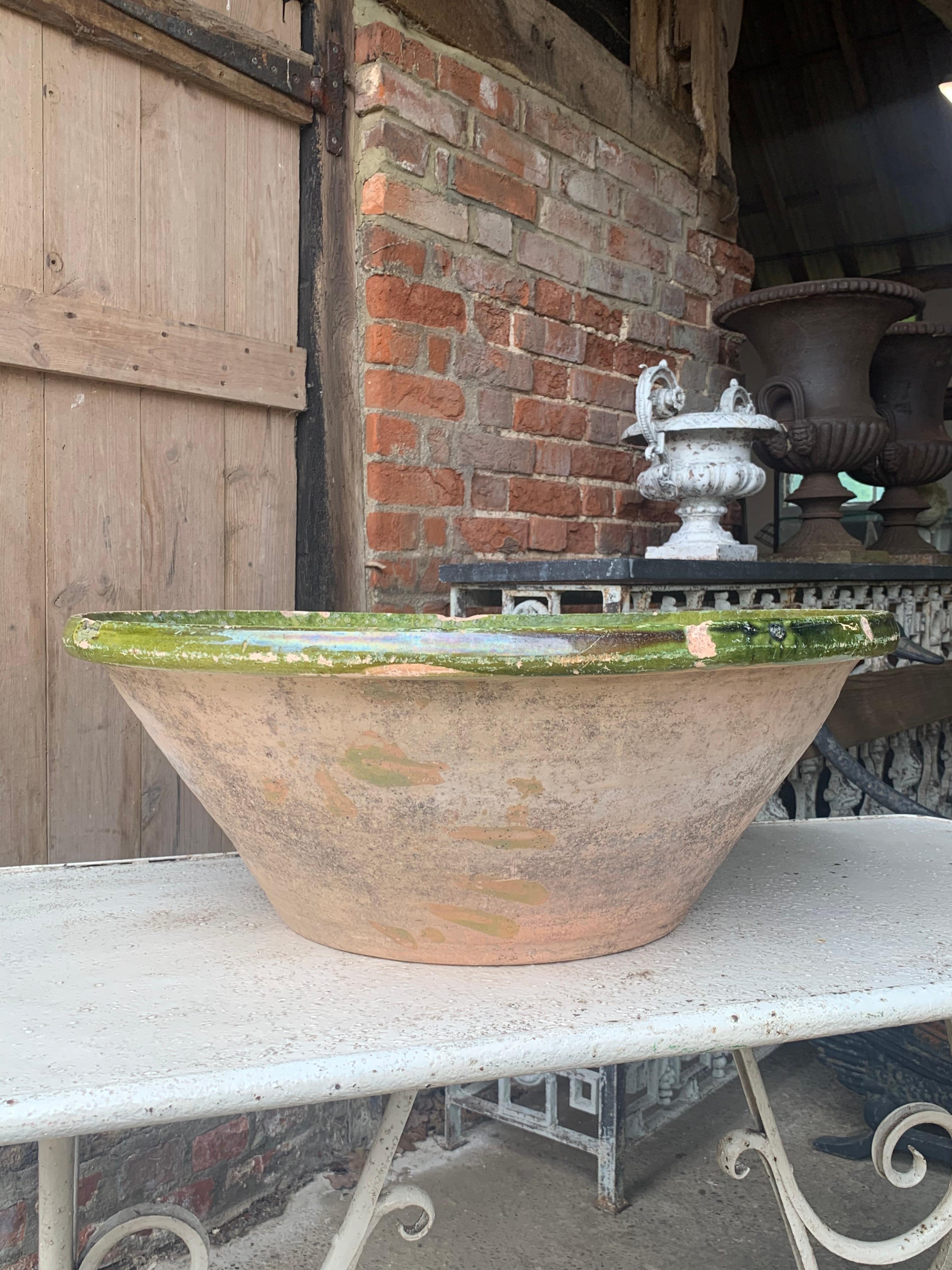 A large 19th century French earthenware Tian bowl with a wonderful green glaze. These were used as mixing bowls in the south of France near the Spanish border. They now make wonderful decorative pieces.

You can see the makers handprint on one side