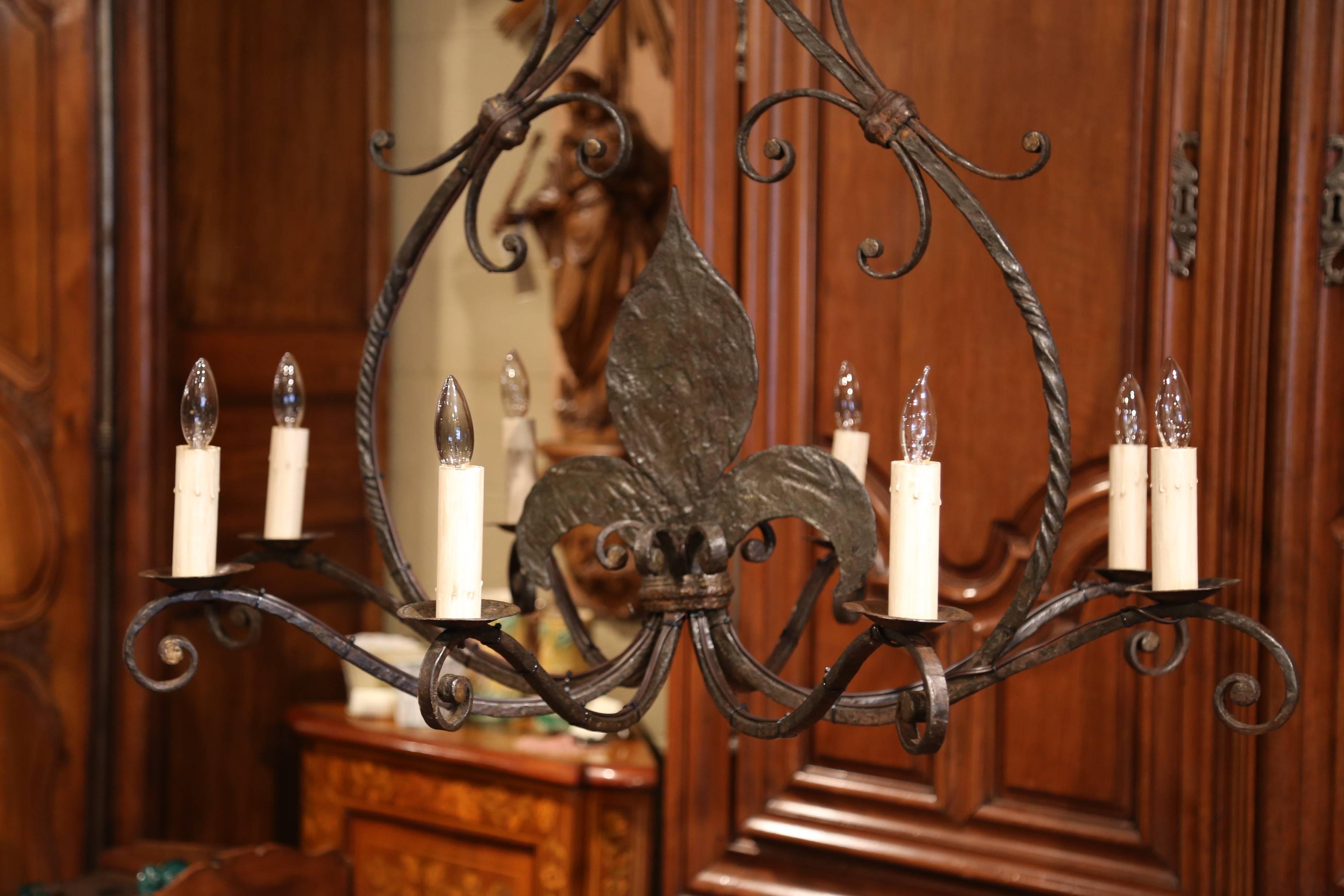 Add a touch of Gothic style to your house with this elegant light fixture from France. Forged in Normandy, circa 1880, the antique chandelier has eight newly wired lights, and features a large fleur-de-lys in the centre. The large, rustic chandelier
