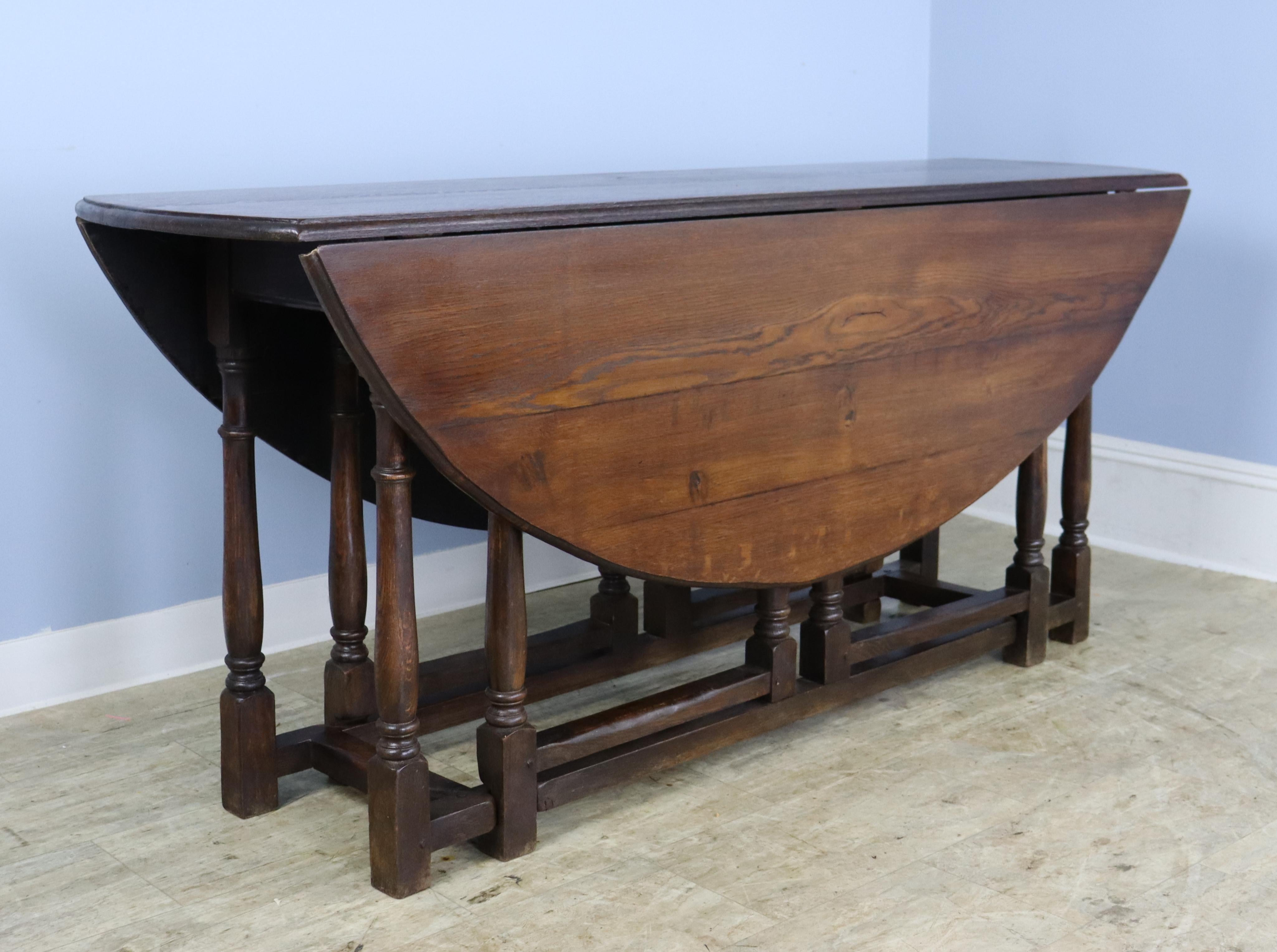 A dropleaf table in rich English oak, to be tucked away or used as an elegant sofa table.  It opens to a large oval which can seat 6 when the legs are opened all the way, or 8 when opened on the diagonal.  (See images 4 and 5).  The turned legs lend
