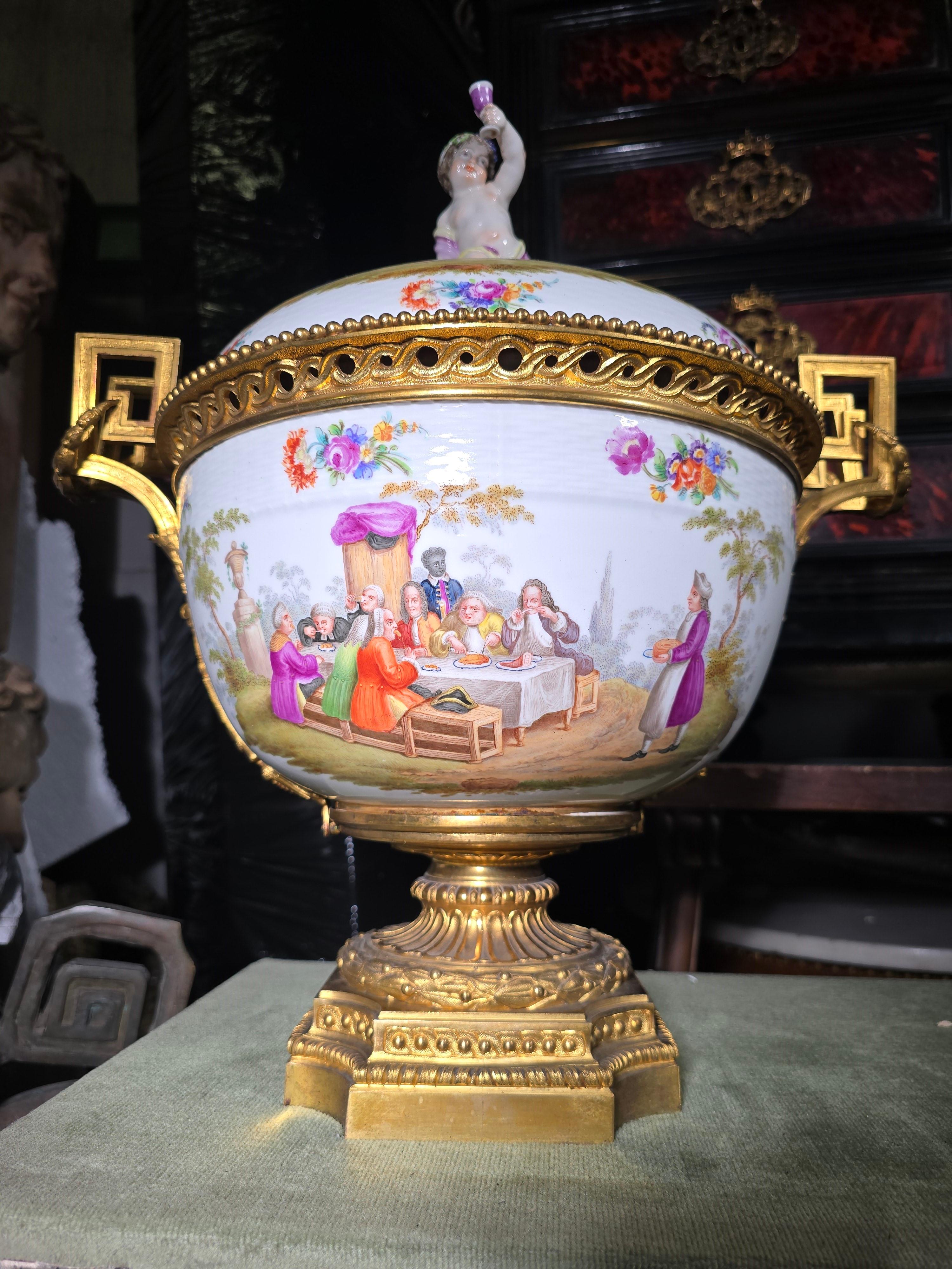 Cet exceptionnel centre de table en porcelaine allemande du XIXe siècle est un magnifique exemple de l'art et de l'artisanat européens. Montée sur un bronze doré finement travaillé, la pièce est ornée de scènes peintes de manière exquise