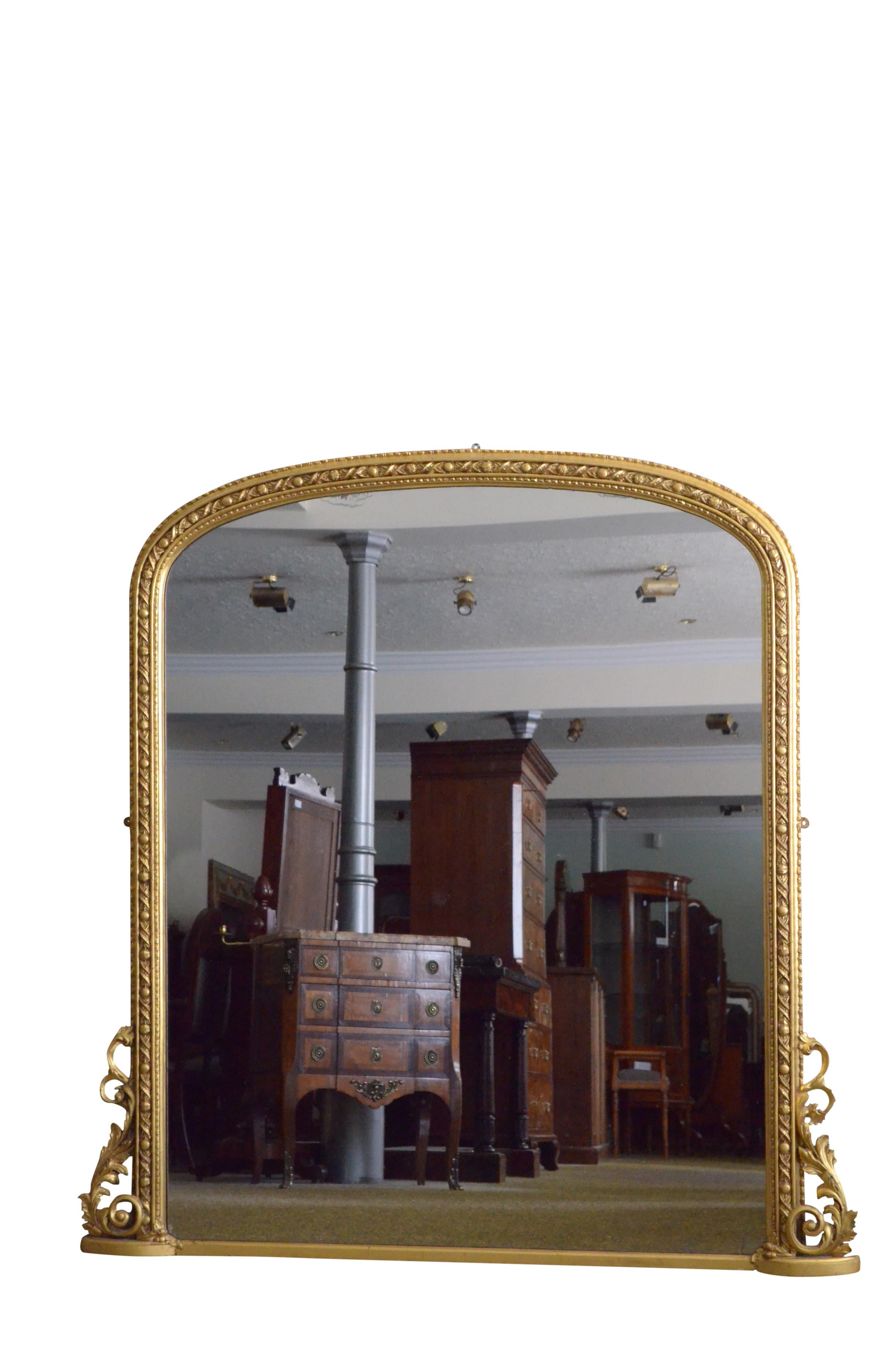 K0517 A large XIXth century gilded wall mirror of arched form, having original glass with some foxing in finely carved frame with twisted floral motifs, harebells to the edge and elaborate floral scrolls to the base. This antique mirror is in