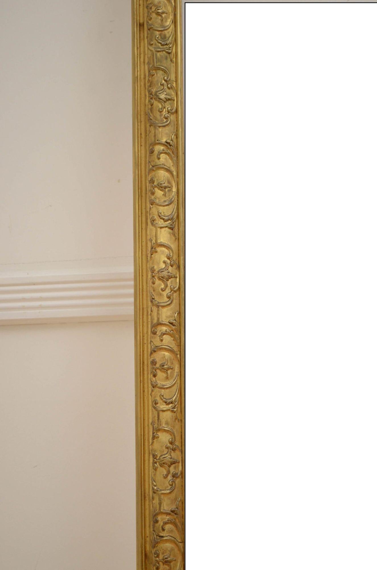 Sn5009 Superba specchiera dorata da parete o da appoggio del XIX secolo, con vetro di ricambio in una cornice in legno dorato decorata a stampo e a volute con stemma centrale a conchiglia affiancato da campanelle. Questo specchio antico conserva la