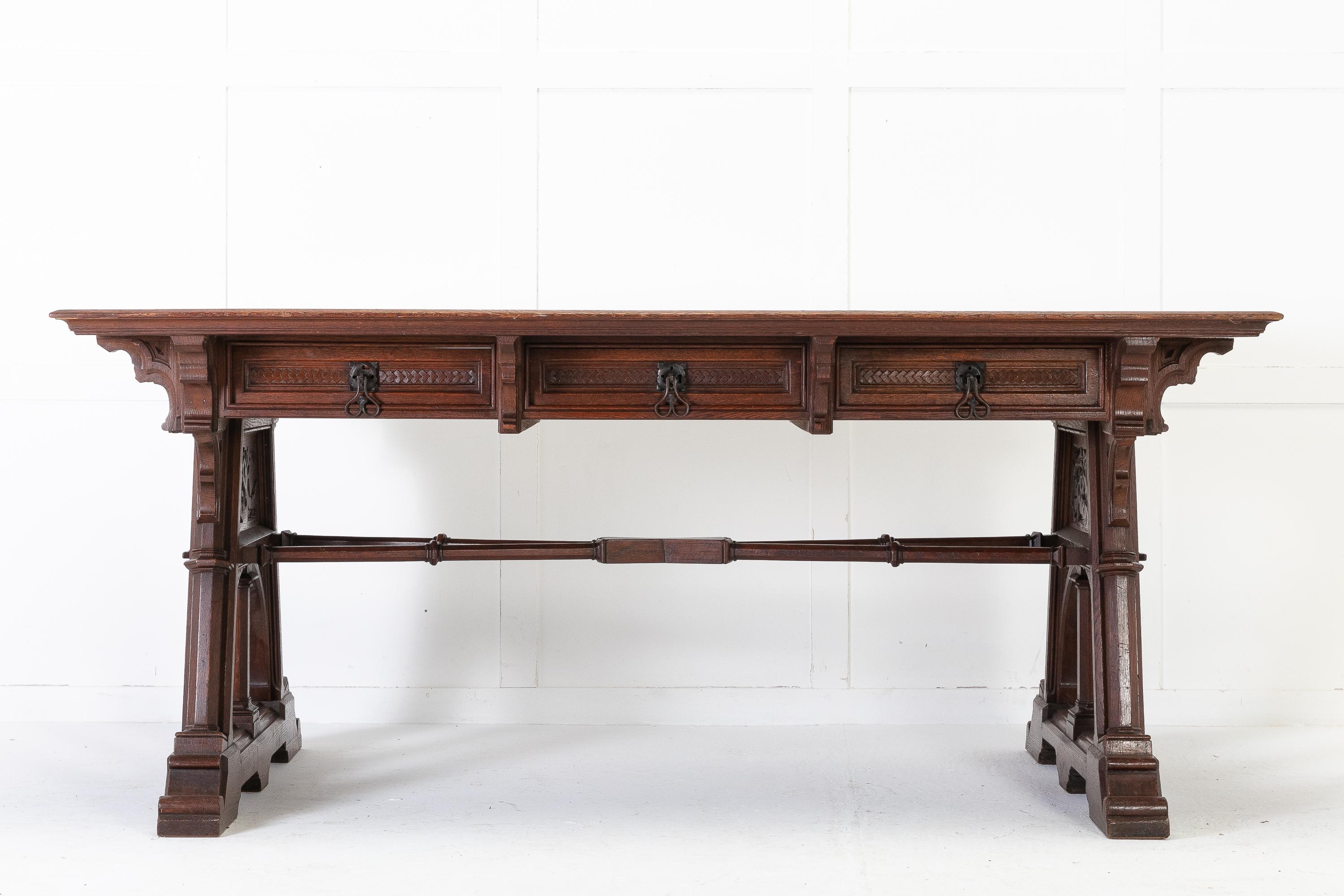 An impressive and large 19th Century gothic oak desk having a rectangular cross banded marquetry top with large overhang. Three frieze drawers with scroll corner and central brackets. Supported by unusual angled ends with pierced fretwork and