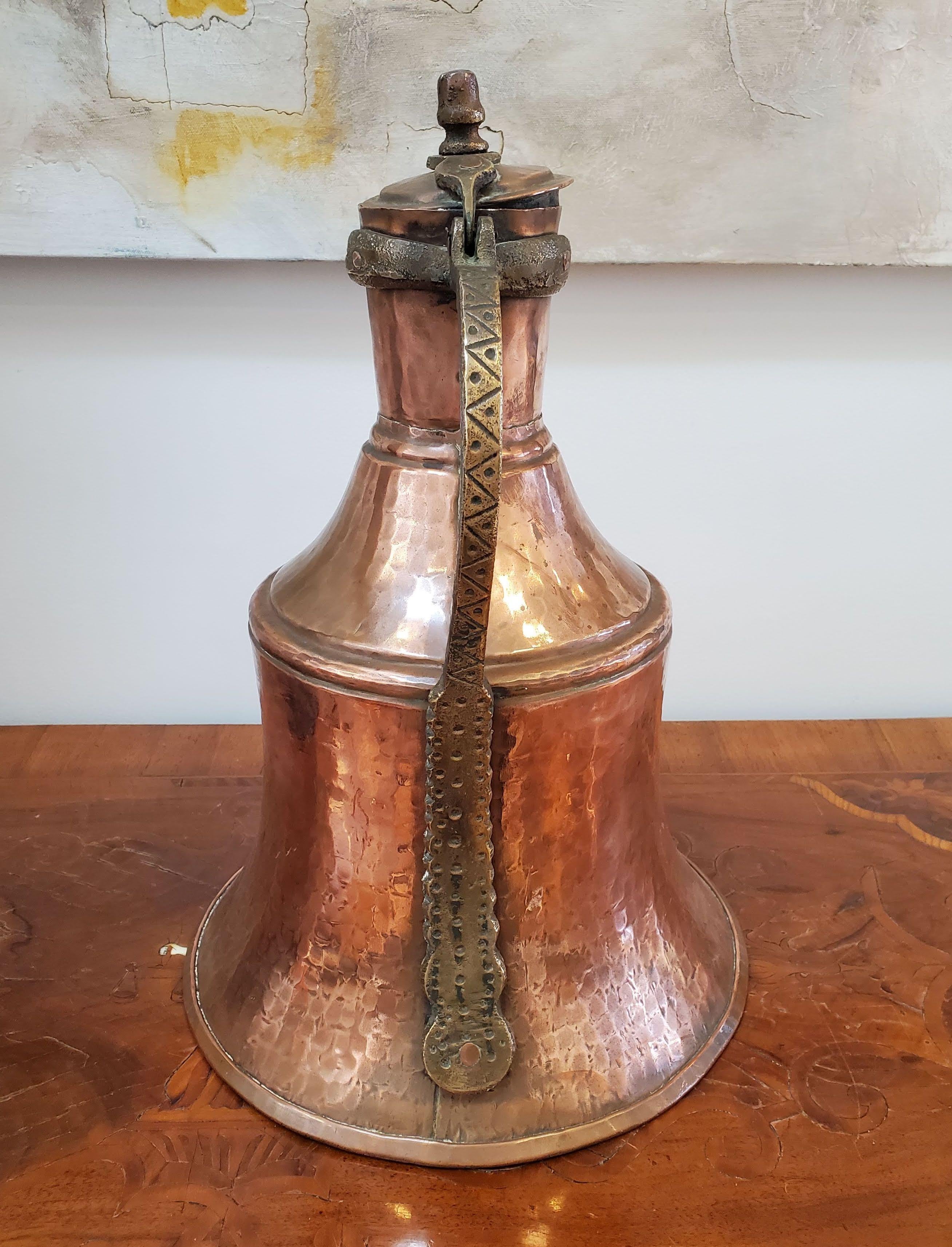 Rare large 19th century copper wine ewer. Good old patinated surface. Great proportions and interesting shape with lid and heavy brass riveted handle on hand “hammered” surface. 
North Africa, circa 1870
Measures: 17” Height, 11.5” Diameter.
 
