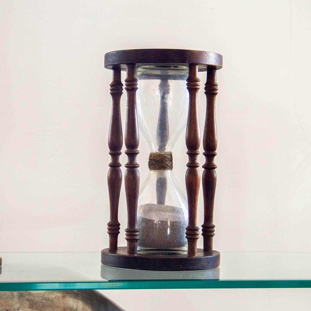 A large 19th century hourglass with clear glass blown bulbs woven together, the sand timer is housed within a wooden stand, which has circular ends joined by four turned balusters.

Excellent antique condition.