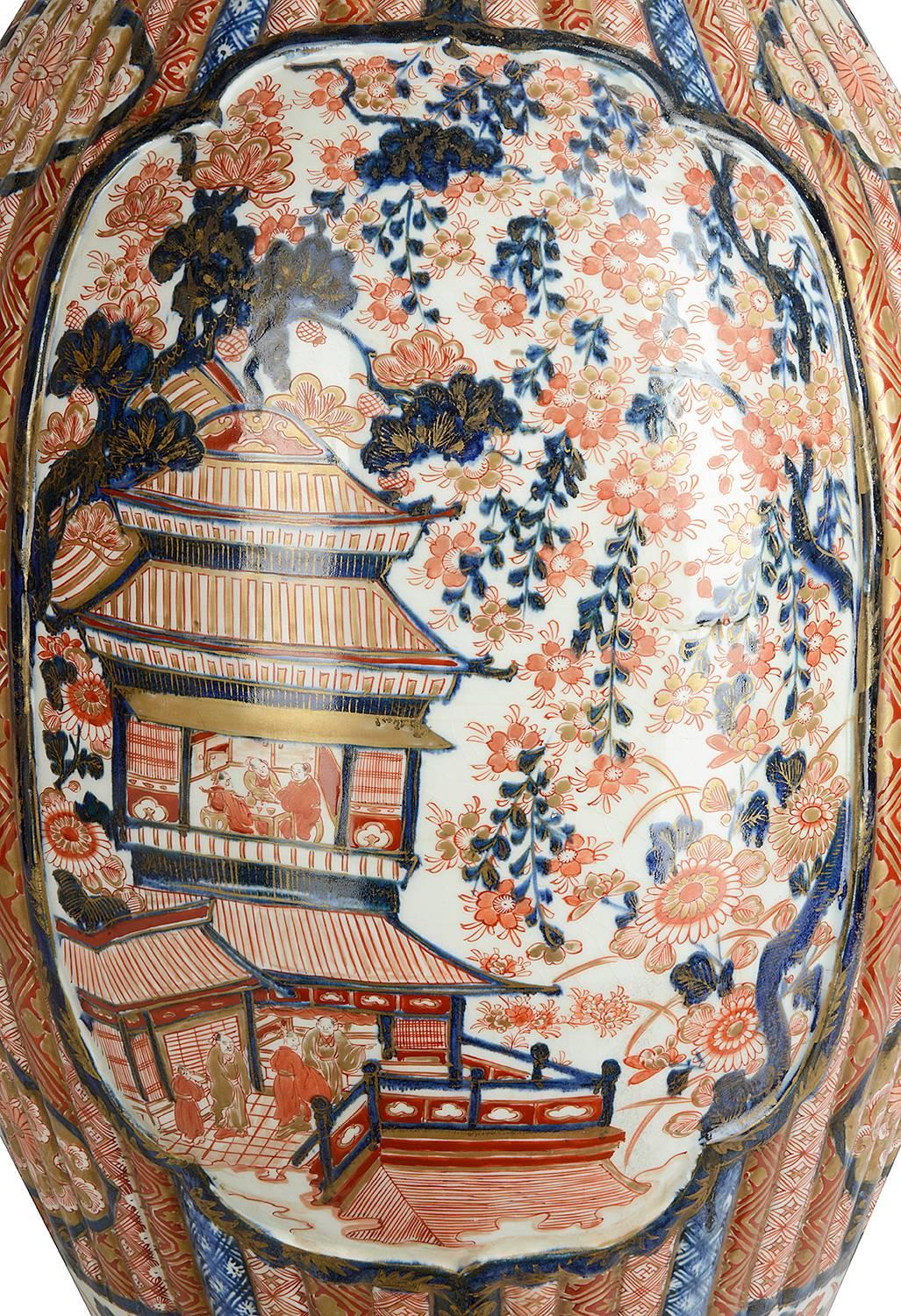 A large and impressive 19th century Japanese Imari Vase, having classic Imari orange, red and blue colors. Traditional motifs to the ground. Mythical birds amongst flowers, the body of the vase having raised reeded form with geometric patterns, with