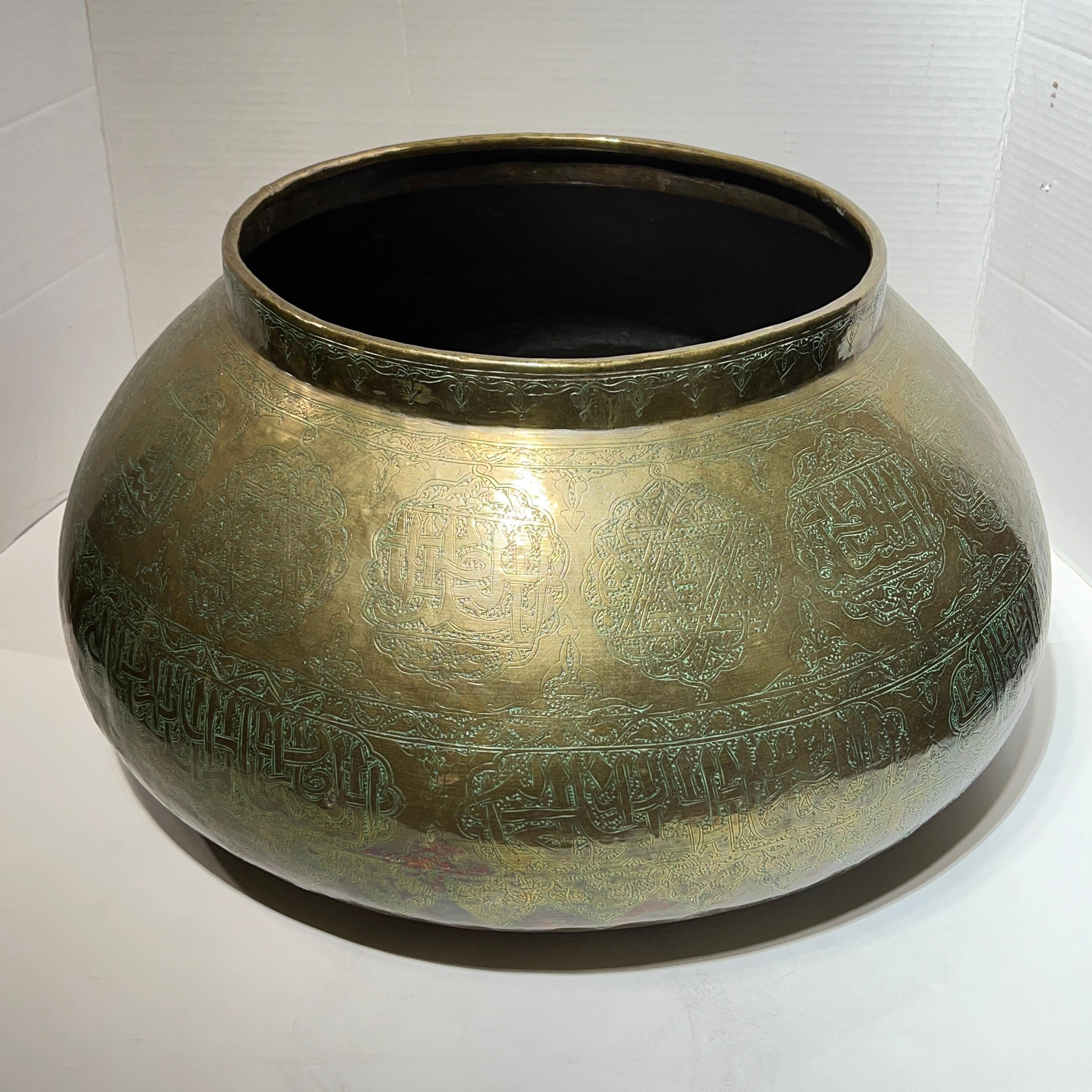 Very large, hand-hammered Islamic brass bowl with fine engraved calligraphy and poetry in Arabic measuring 20.5 inches across and 11 inches tall.
