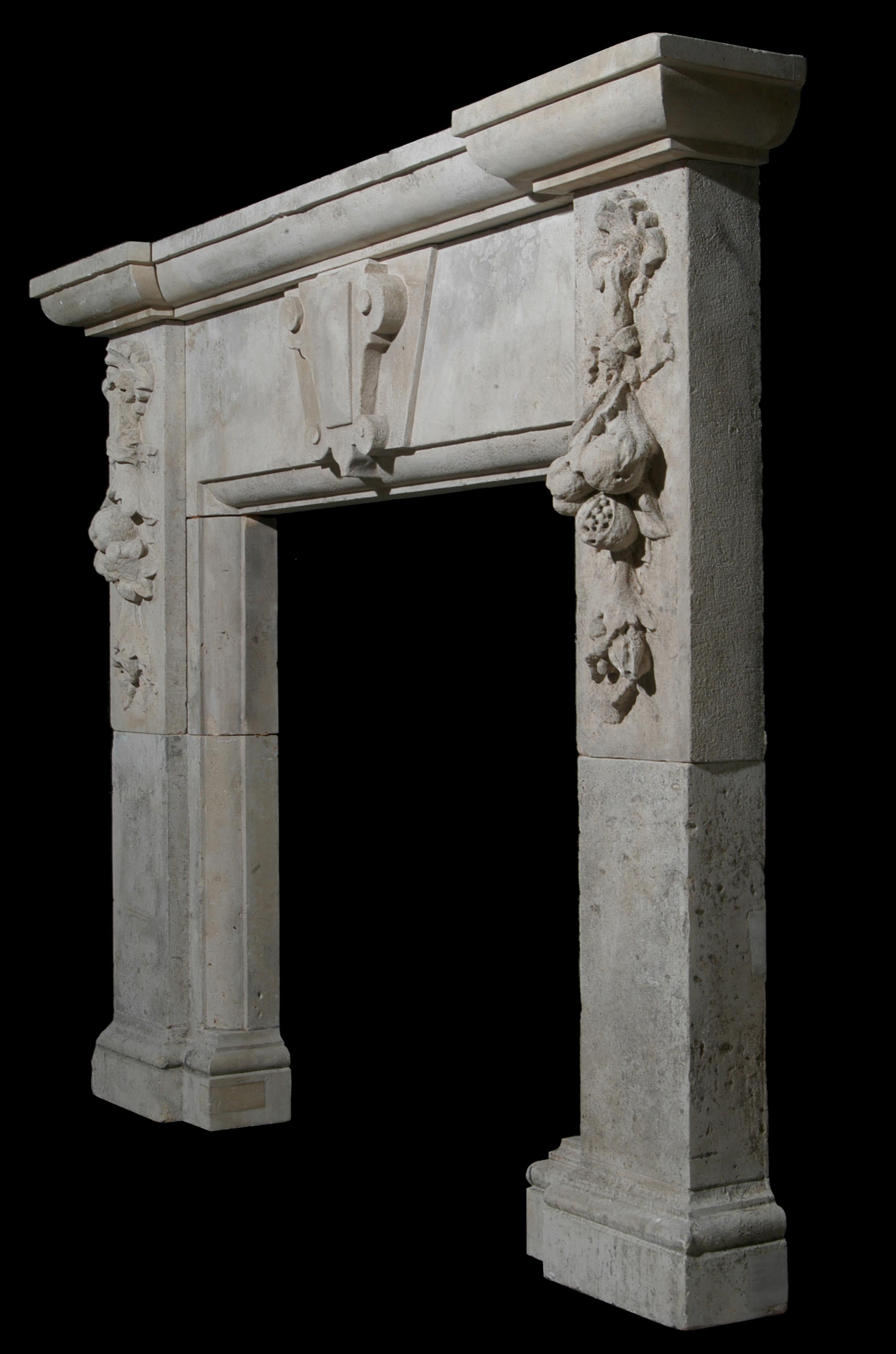 Cheminée de style Renaissance en pierre calcaire, bien sculptée, avec une clé de voûte centrale sur la frise, et des chutes de rubans et de fleurs profondément sculptées sur les jambages, surmontée d'une étagère en trois parties sur le front de