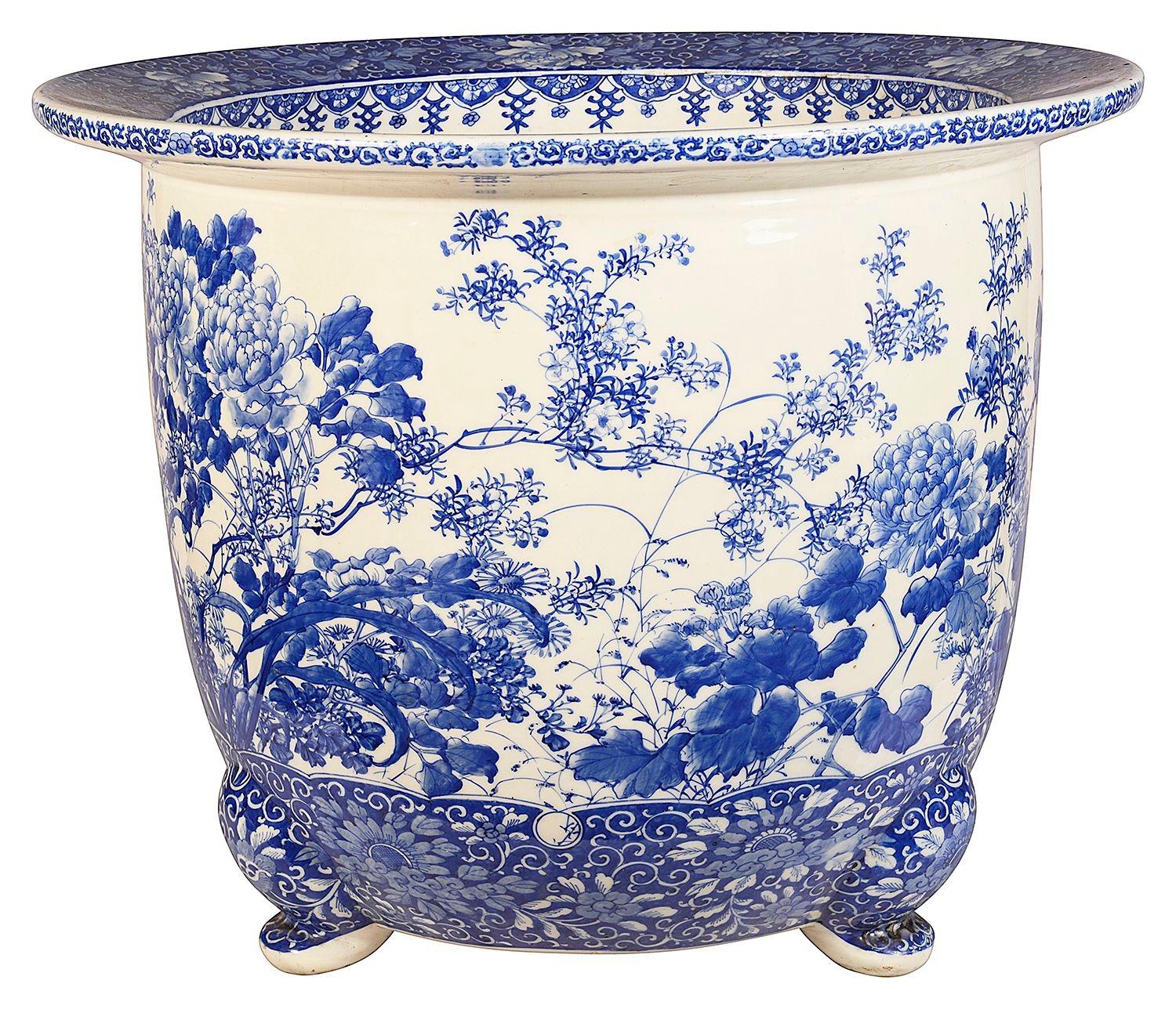 Grande jardinière japonaise en porcelaine bleue et blanche, ornée de magnifiques motifs traditionnels sur le dessus et le dessous. Avec des fleurs exotiques et du feuillage peints à la main. Elle repose sur trois pieds à enroulement. Période Meiji