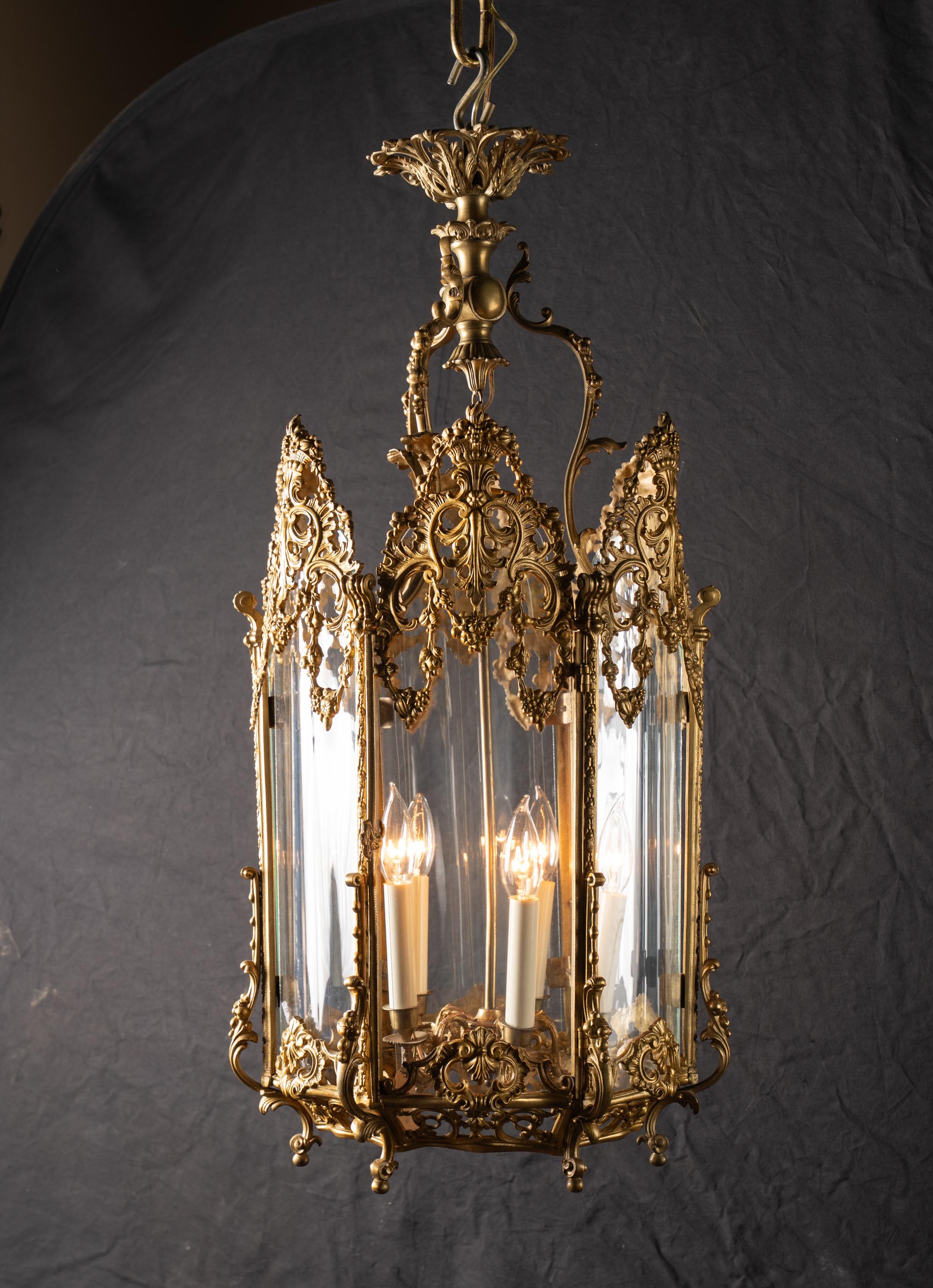 This 19th century Louis XV hexagonal hanging lantern features beautiful reticulated bronze with curved glass panels. The bronze work is plentiful and incredibly ornate, note the crown at top, the pattern work at the top and bottom of each glass