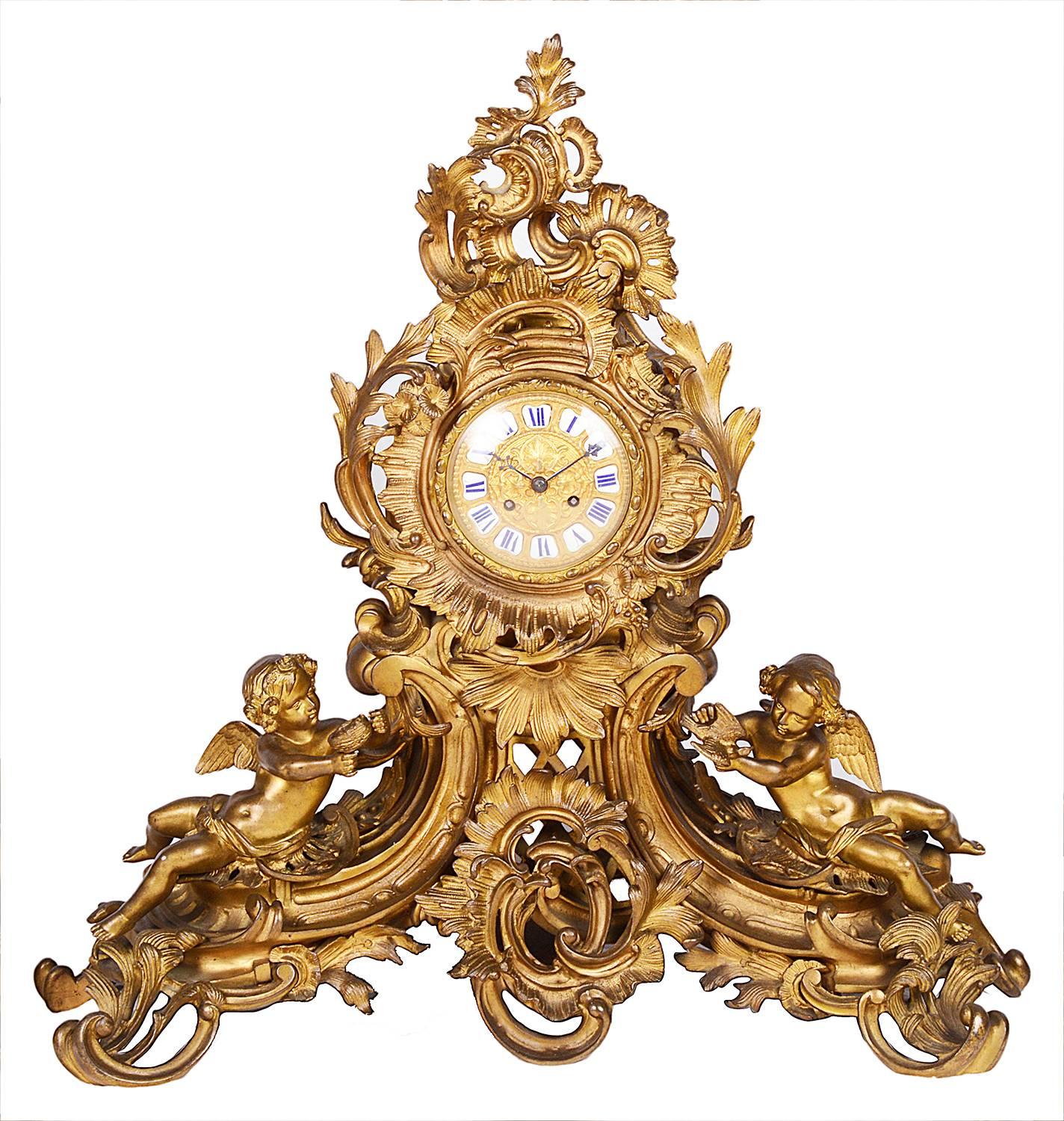 A large and impressive, 19th century gilded ormolu Louis XVI style clock garniture. Having scrolling foliate decoration with cherubs supporting the eight branch candelabra and either side of the clock. The clock having an eight day duration,