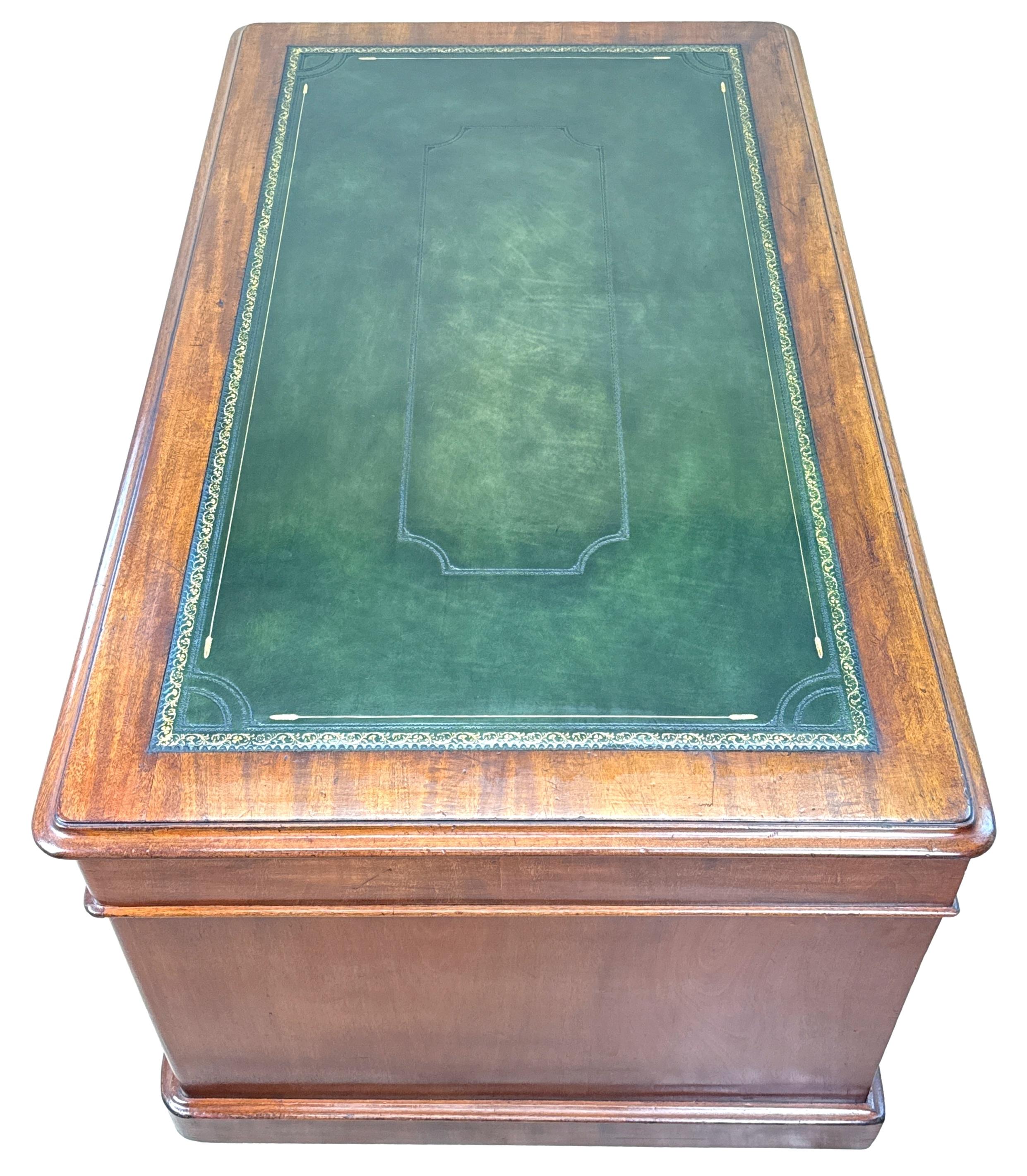Superbe bureau à piédestal en acajou ancien du milieu du XIXe siècle, d'une rare ampleur, doté d'une très belle garniture en cuir doré de remplacement sur le dessus à bandes croisées, de neuf tiroirs en frise dotés de boutons en bois tourné