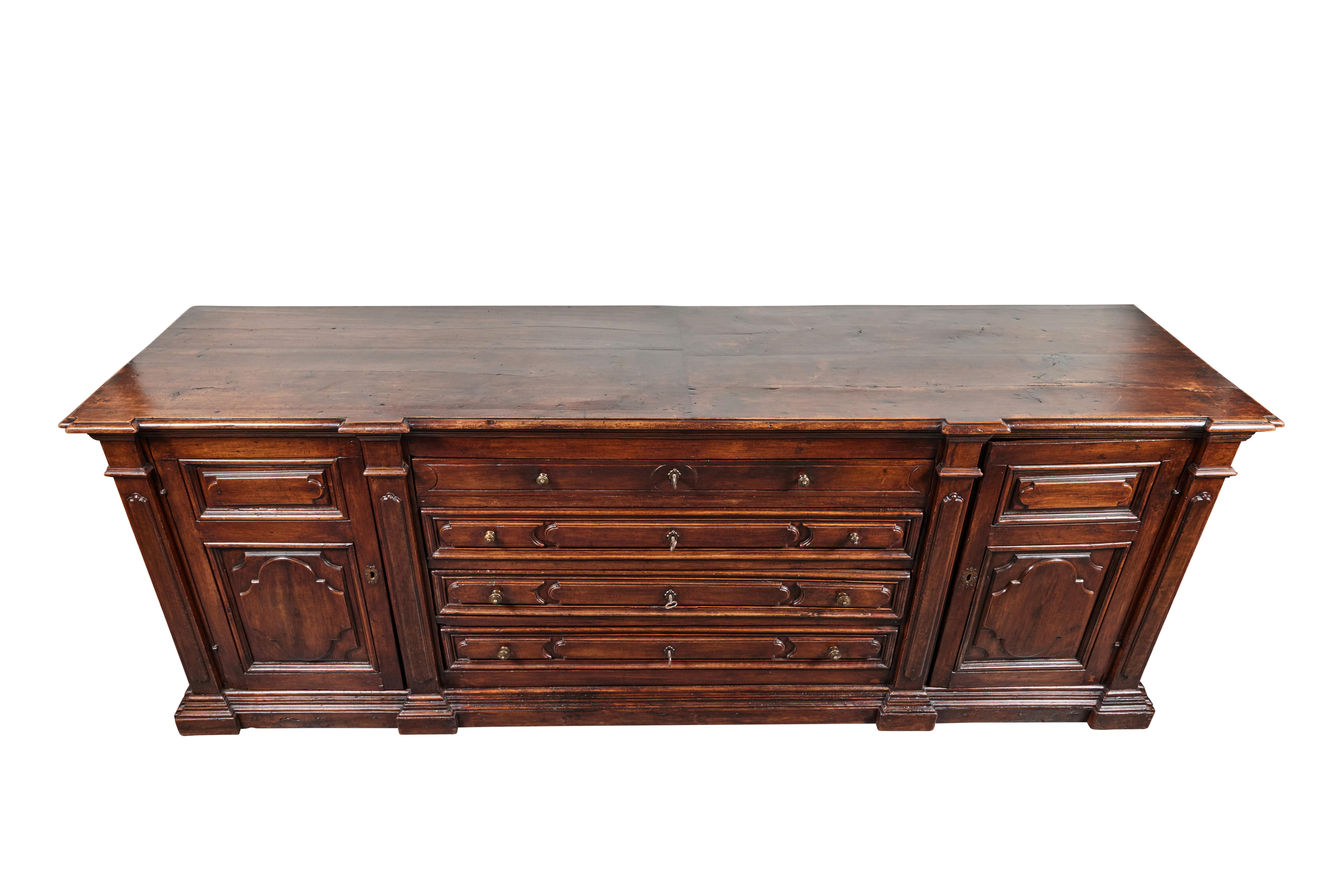 A c. 1870, solid walnut, Italian, hand-carved credenza with relief raised panels throughout. The four central drawers flanked by drawers and bracketed by faux pilasters. The whole on a stepped base.