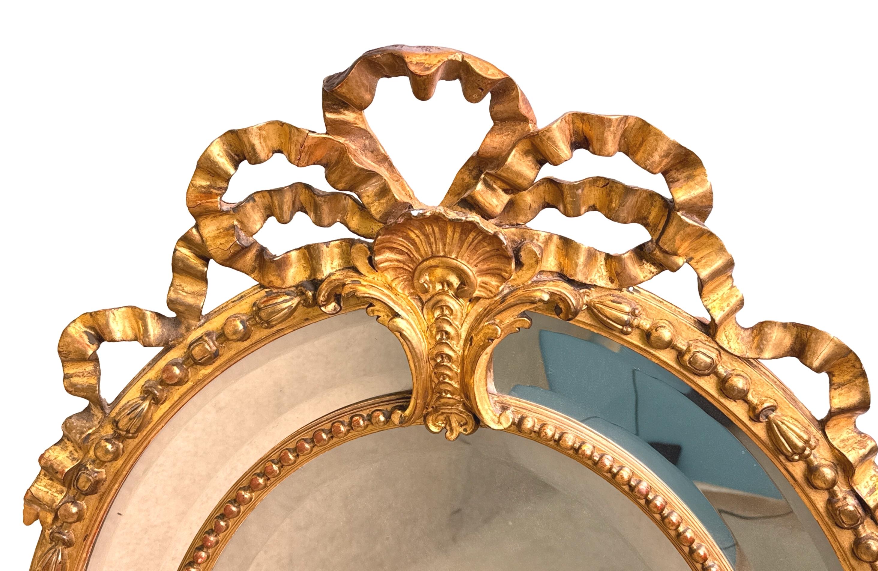 Specchio ovale da parete in legno dorato e gesso del XIX secolo, estremamente interessante, con un'attraente cornice intagliata a nastro, sopra una cornice a doppio bordo segmentato, con decorazioni intagliate in modo superbo, tra cui gusci